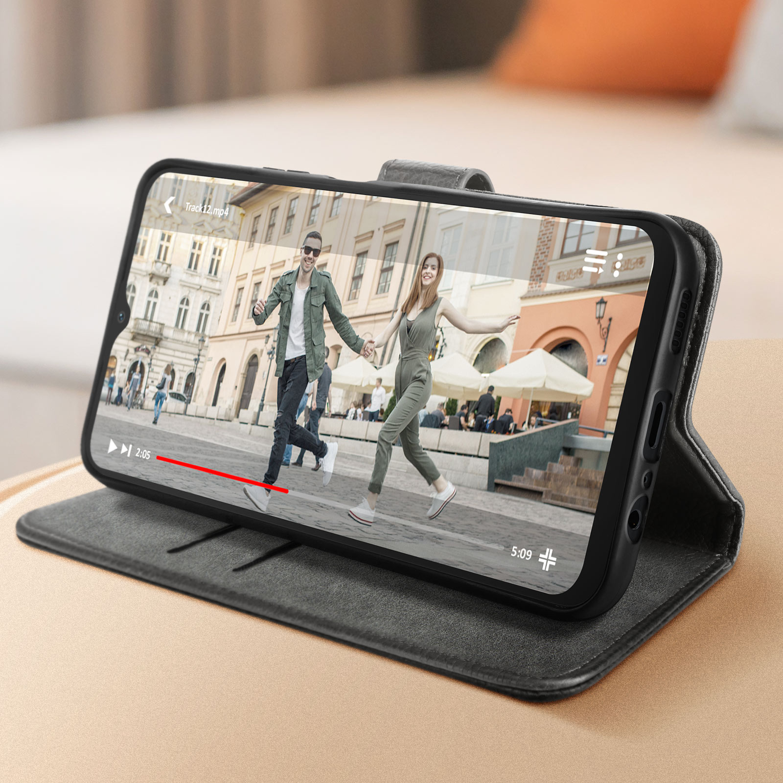 Ein Smartphone in einer Hülle zeigt ein Video eines Paares, das in einer Stadt spaziert. Die Hülle ist offen.
