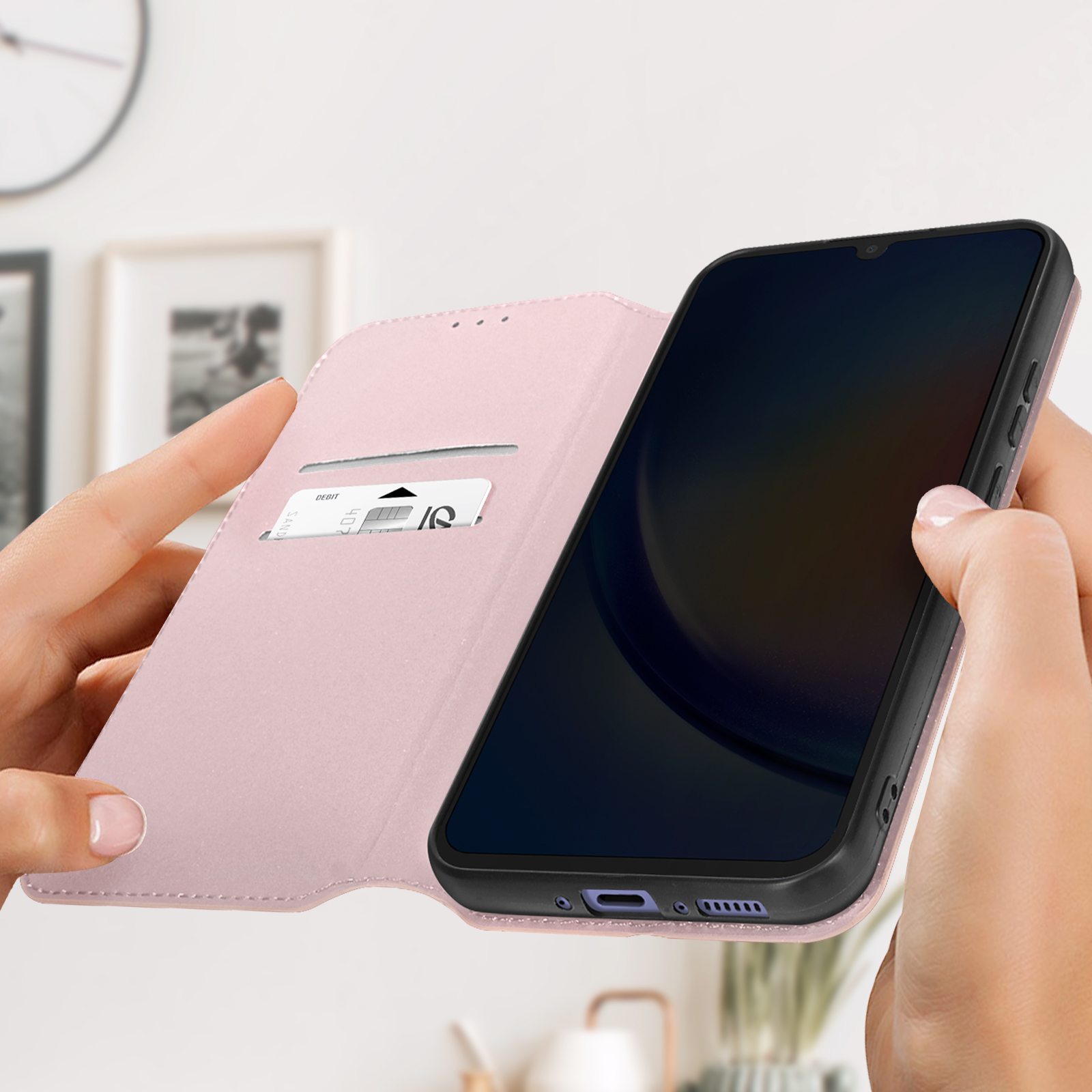 Mano che tiene una custodia rosa per telefono con un telefono nero. La custodia è aperta, che mostra uno slot per schede.