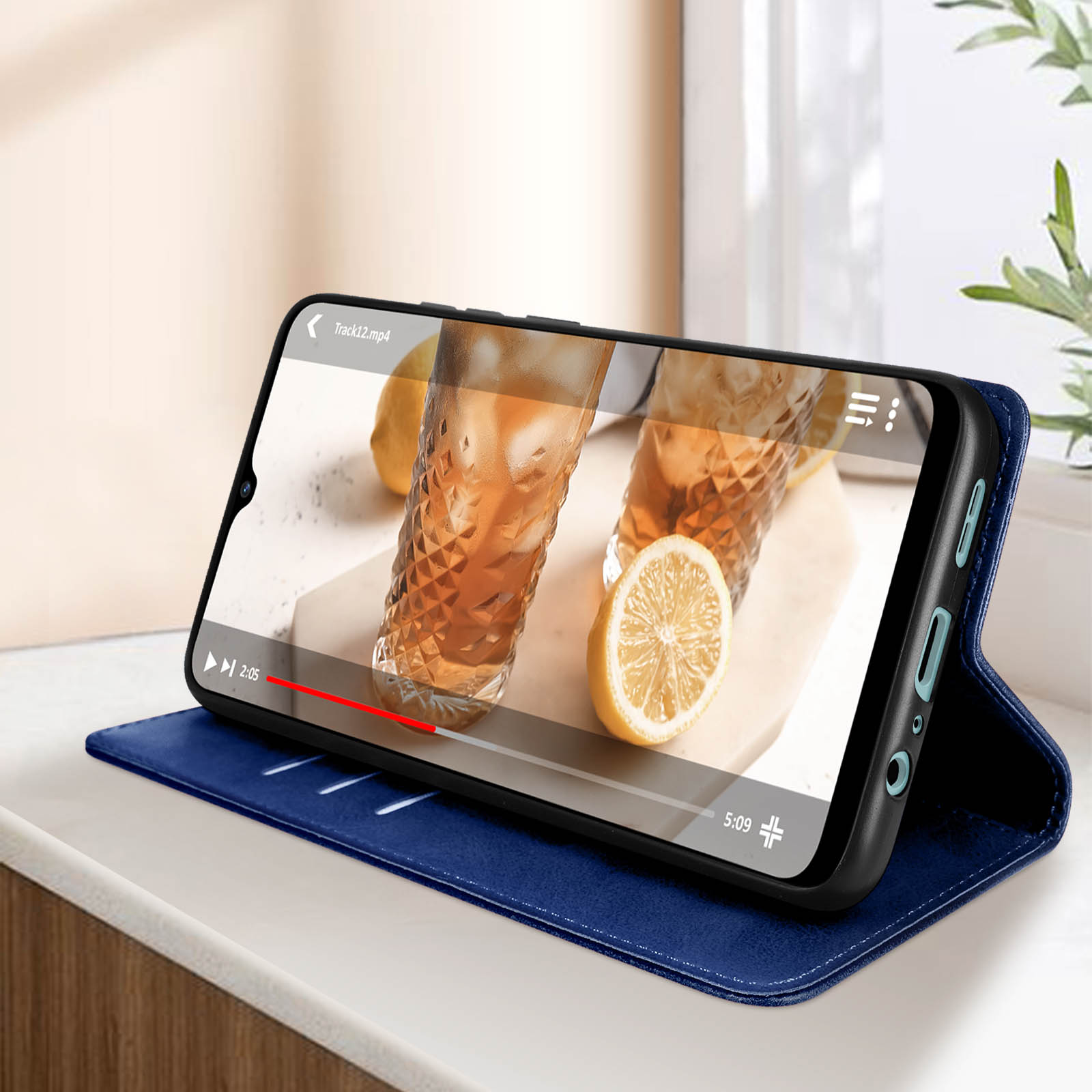 Smartphone in custodia blu che riproduce un video, con limone e bicchiere sul tavolo.