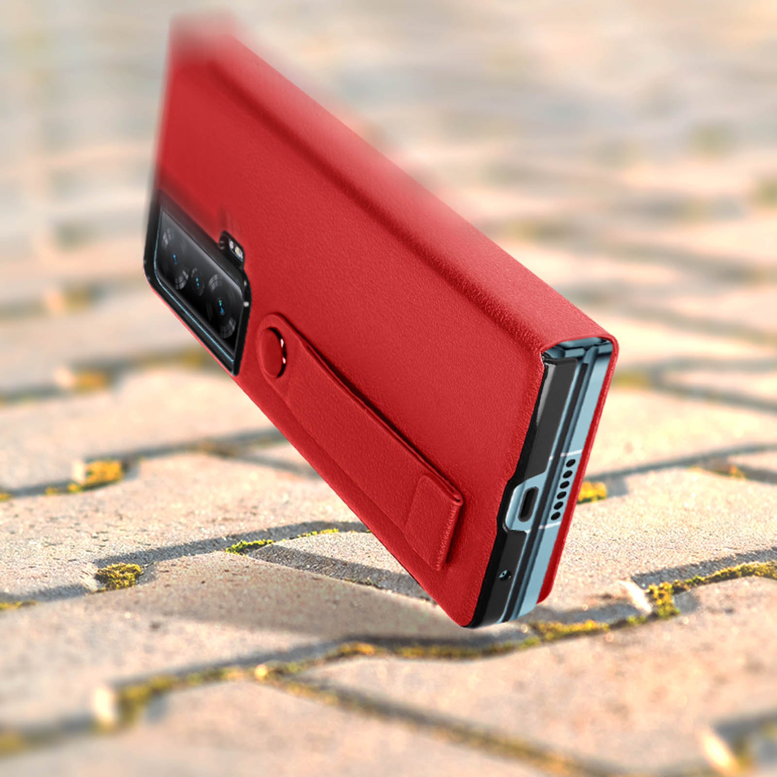 Custodia rossa per telefono in aria. La custodia ha un ritaglio per la fotocamera e un cinturino su superficie ruvida.