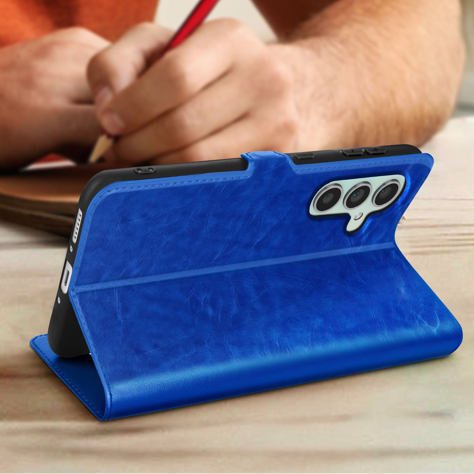 Custodia blu per telefono. Una persona scrive sullo sfondo.
