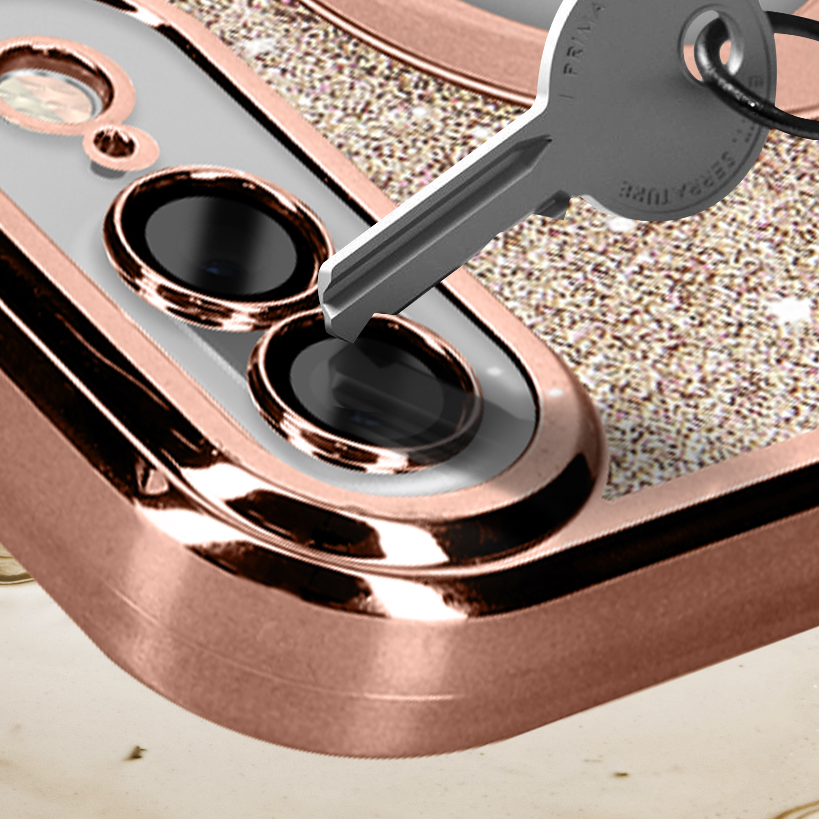 Custodia del telefono con chiave, primo piano. Oro rosa e trasparente con glitter. Su una superficie chiara.