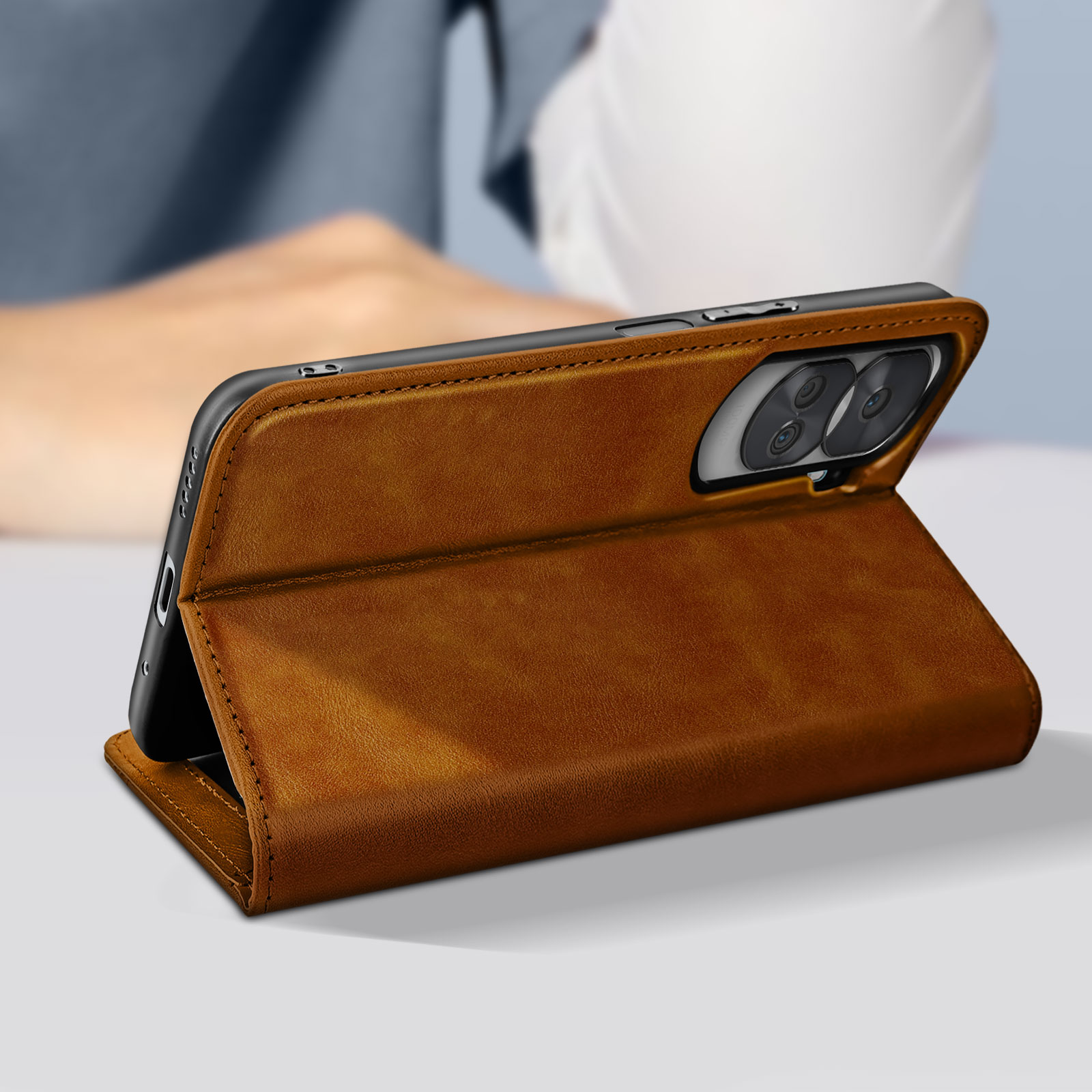 Custodia per telefono in pelle marrone con cuciture, aperta, che rivela telefono e fotocamera. Sfondo sfocato.