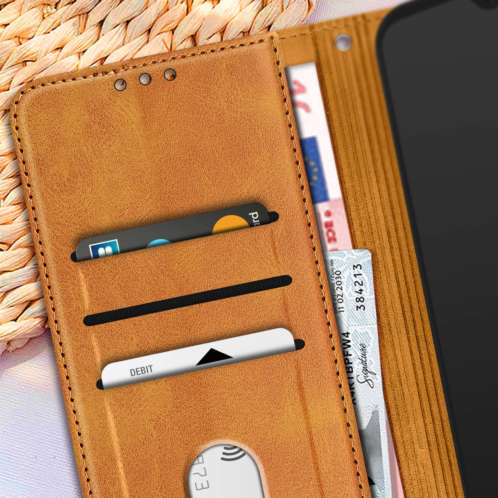 Portafoglio in pelle marrone aperto, con carte e denaro visibili. Un telefono a destra.