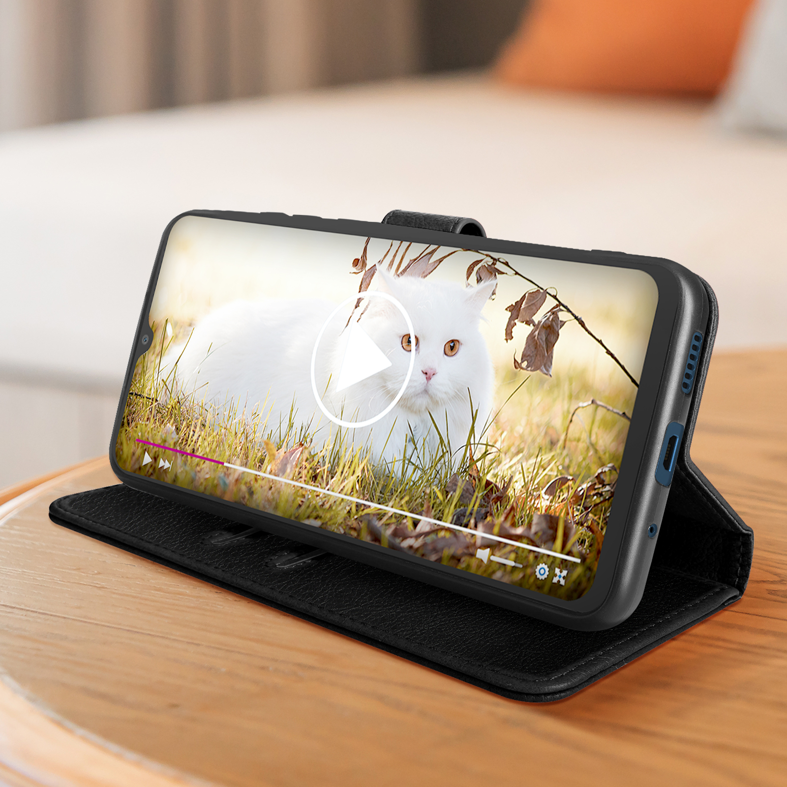 Smartphone in una custodia nera. Un gatto bianco gioca sullo schermo.