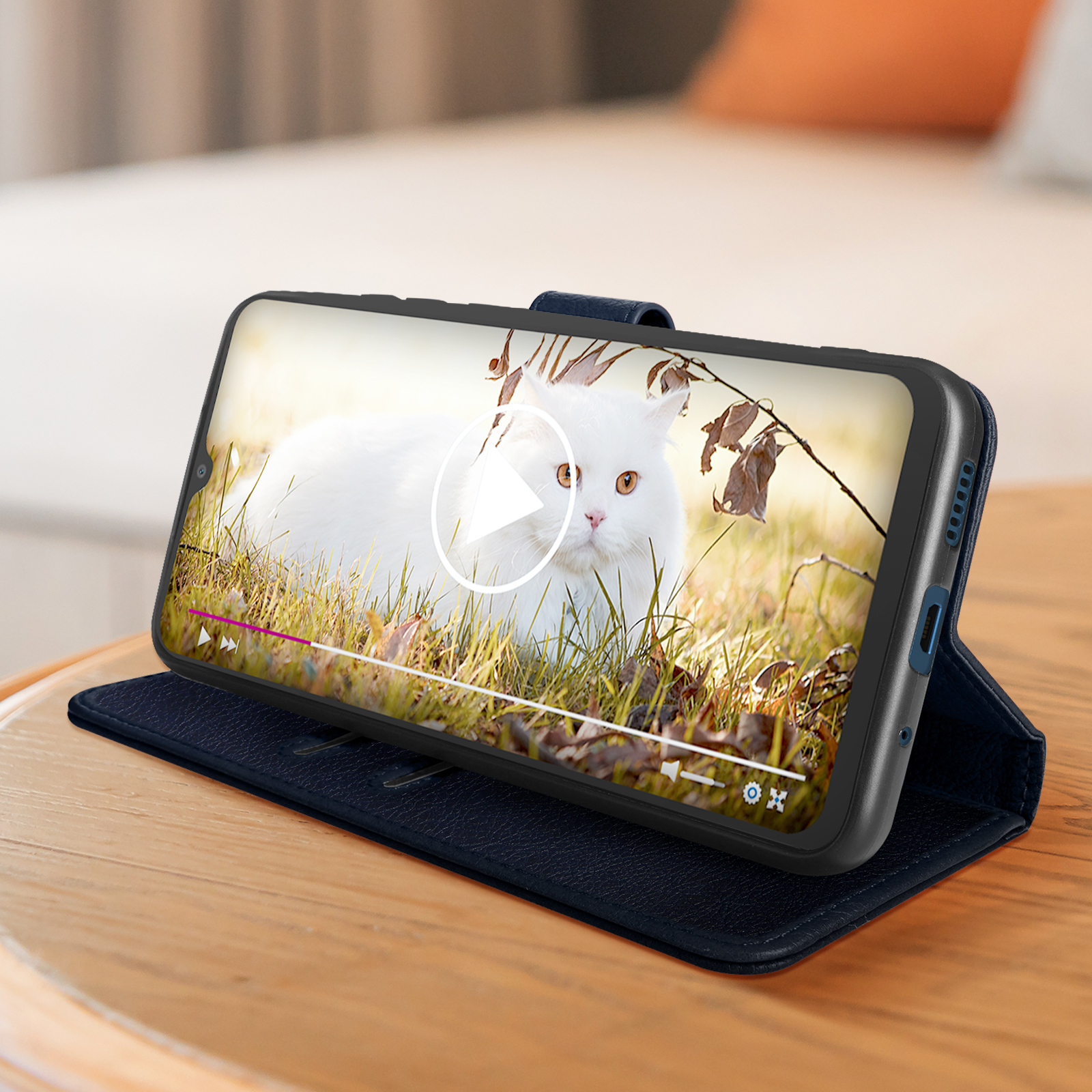 Telefono in una custodia blu, che mostra un video di un gatto bianco nell'erba.