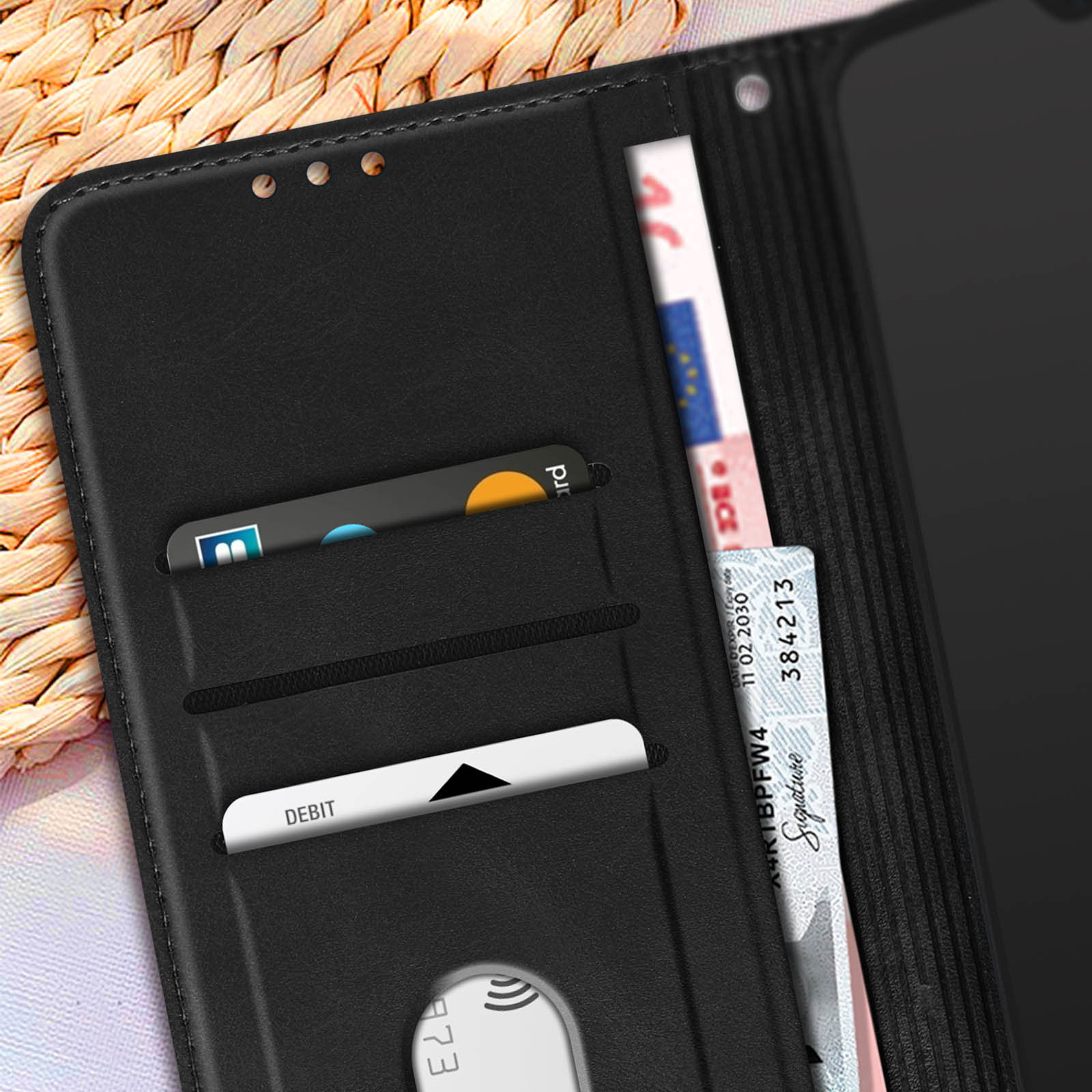 Portafoglio in pelle nera con carte di credito e banconota, su superficie tessuta.