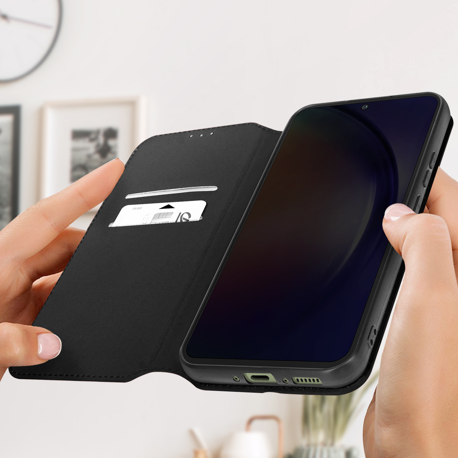 Une personne tenant un téléphone noir dans un étui noir ouvert de style portefeuille.