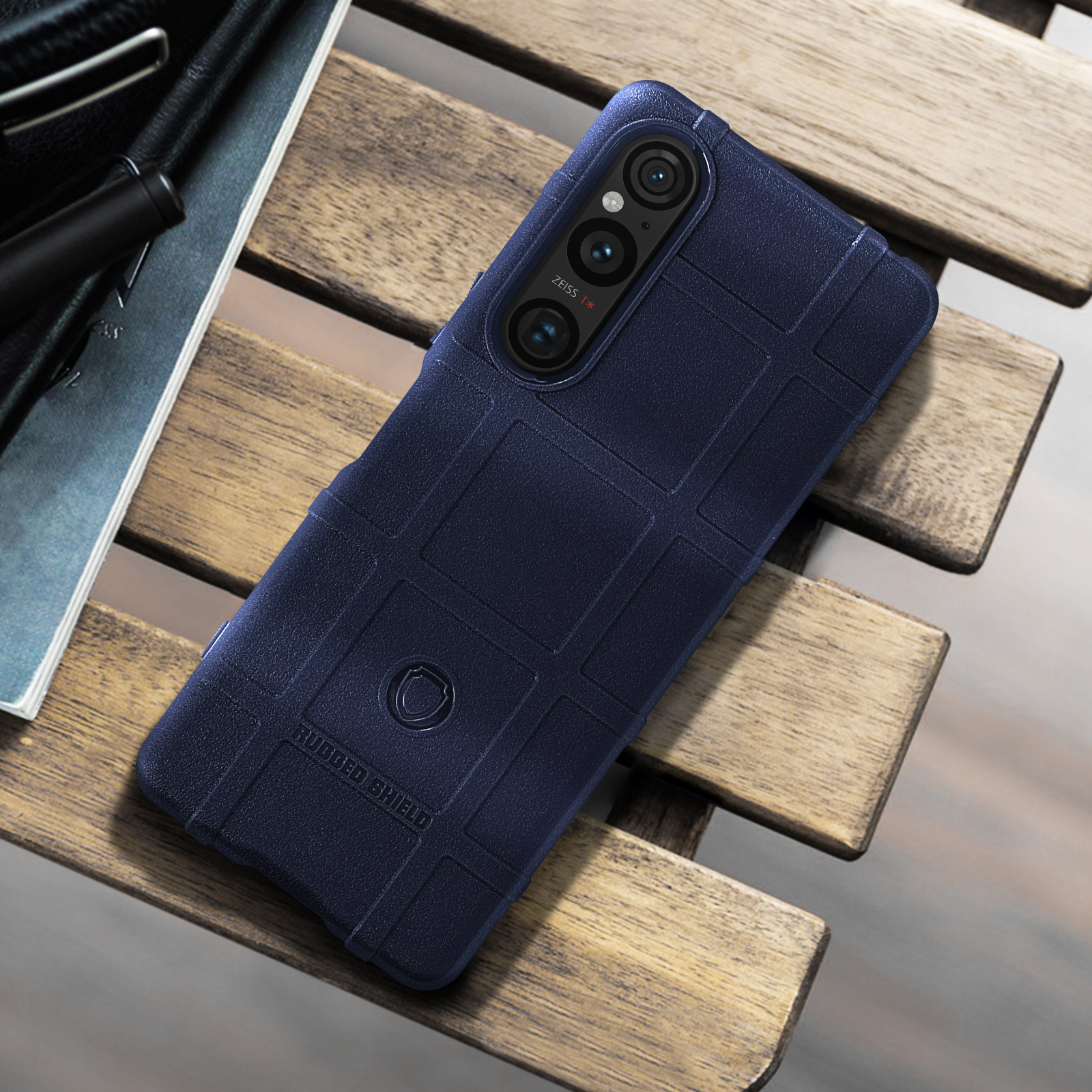 Una custodia blu navy su un tavolo di legno, con una superficie strutturata e una tripla fotocamera.