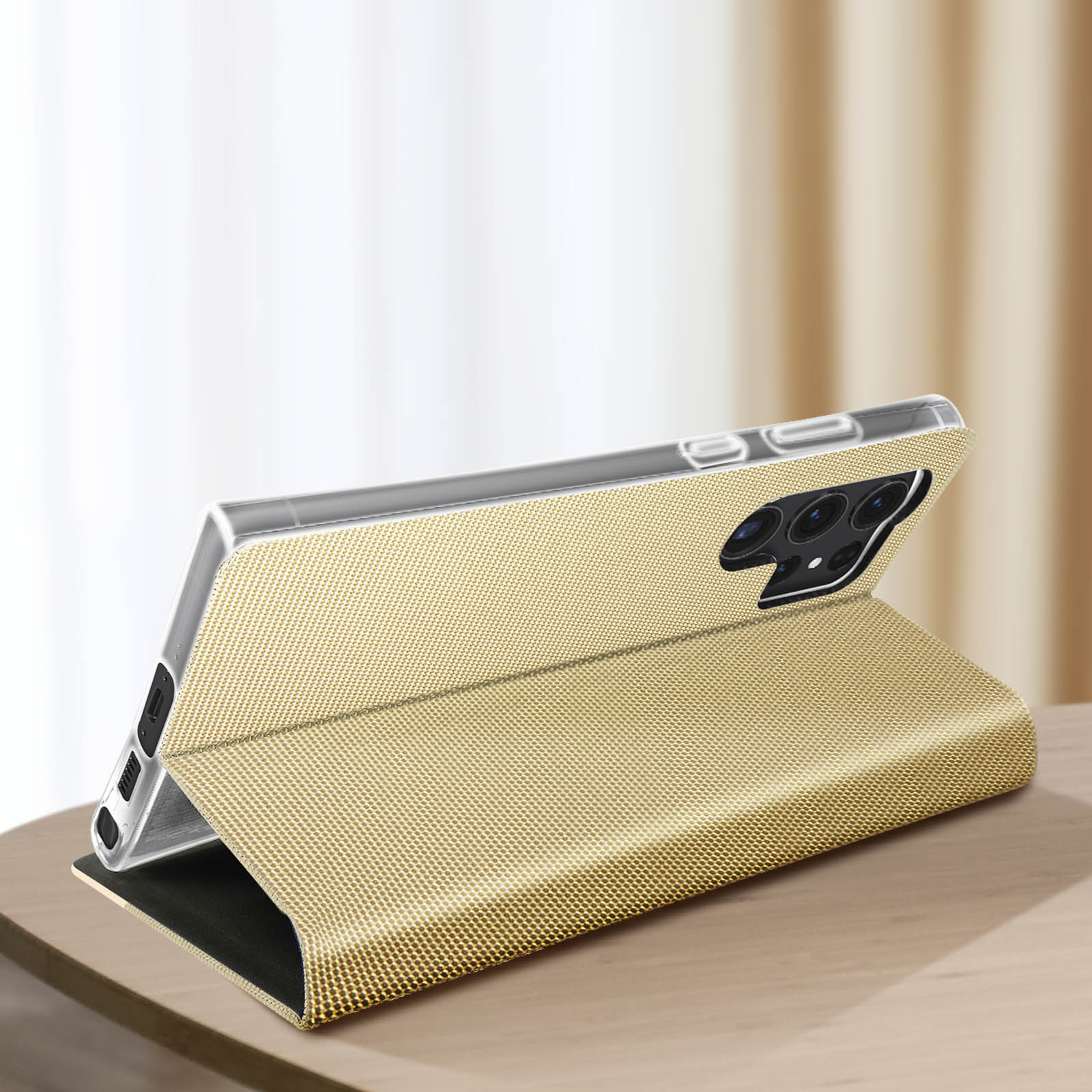 Una custodia dorata per telefono, aperta per mostrare un telefono, su un tavolo di legno. Lo sfondo è sfocato.