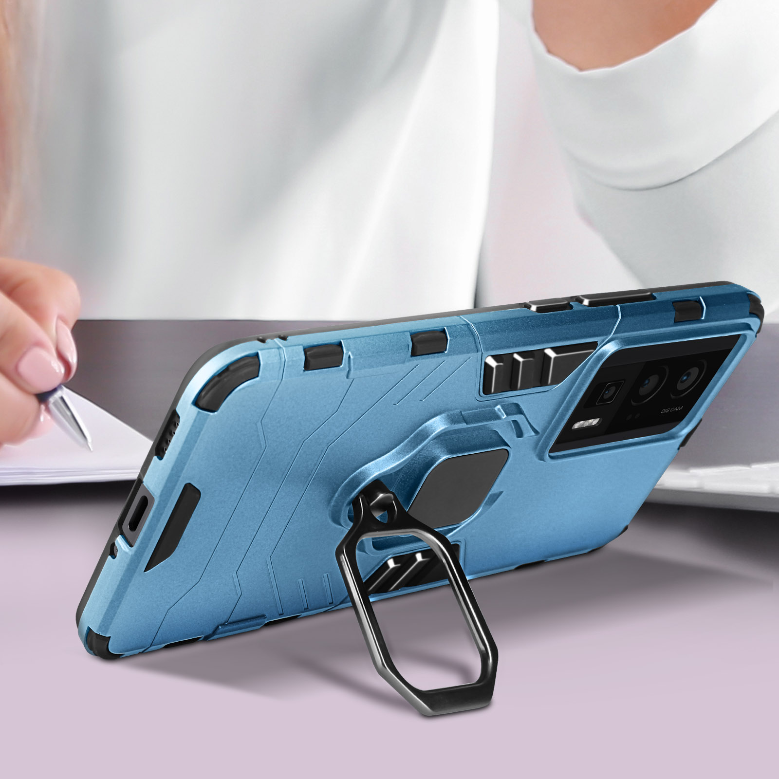 Una custodia per telefono blu con un supporto ad anello. Una persona disegna su carta.