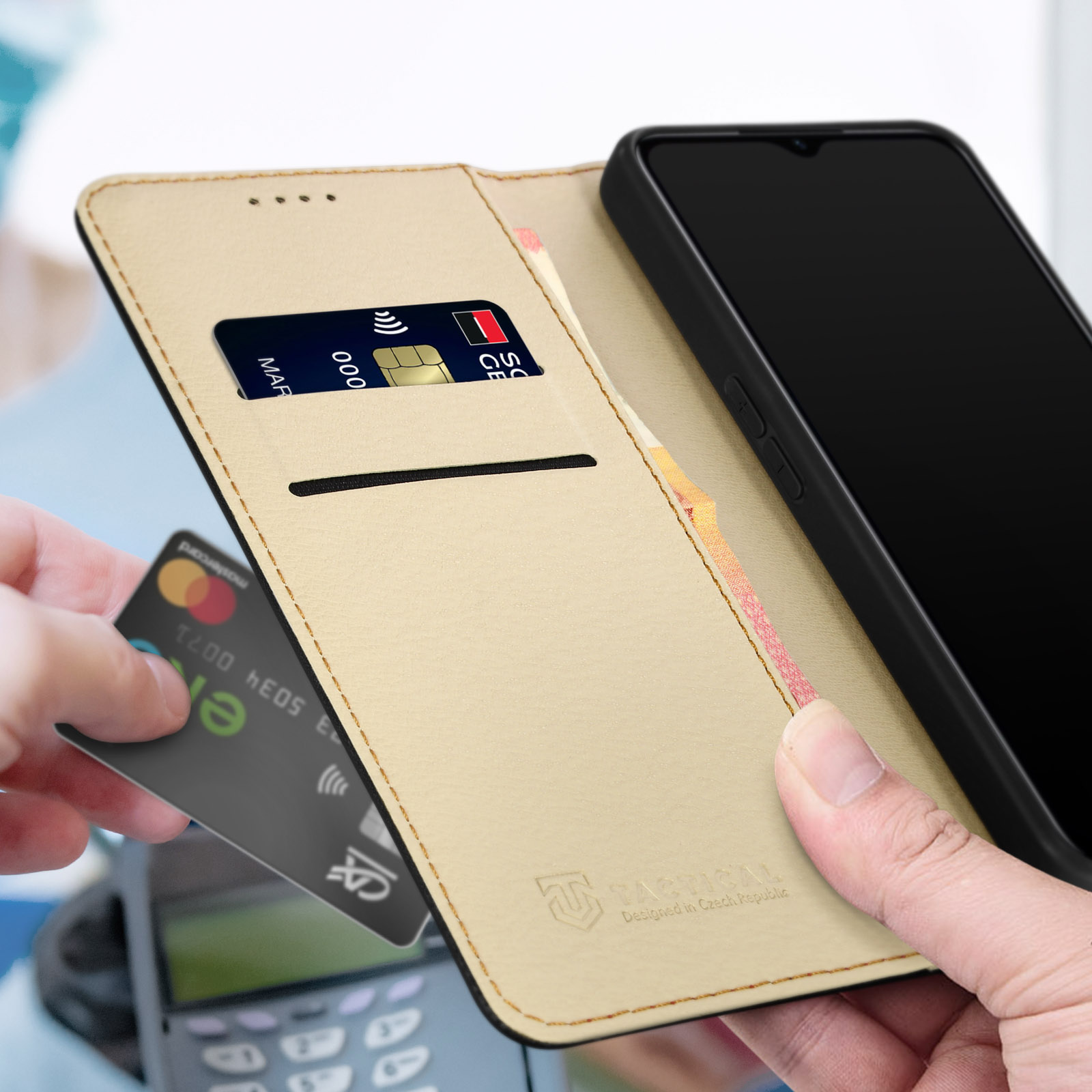 Mano che tiene una carta di credito vicino a un telefono in una custodia a libro.