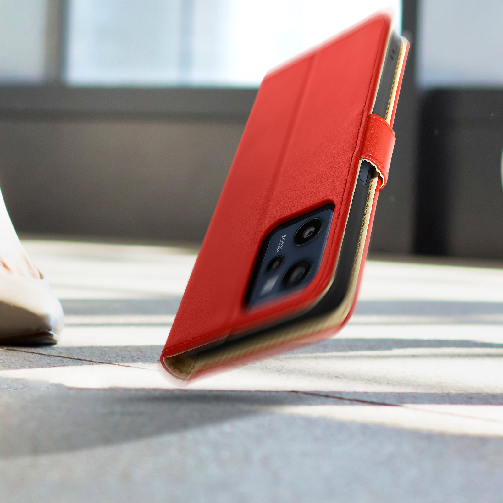 Custodia rossa per telefono con telefono all'interno. La custodia è su una superficie grigia.