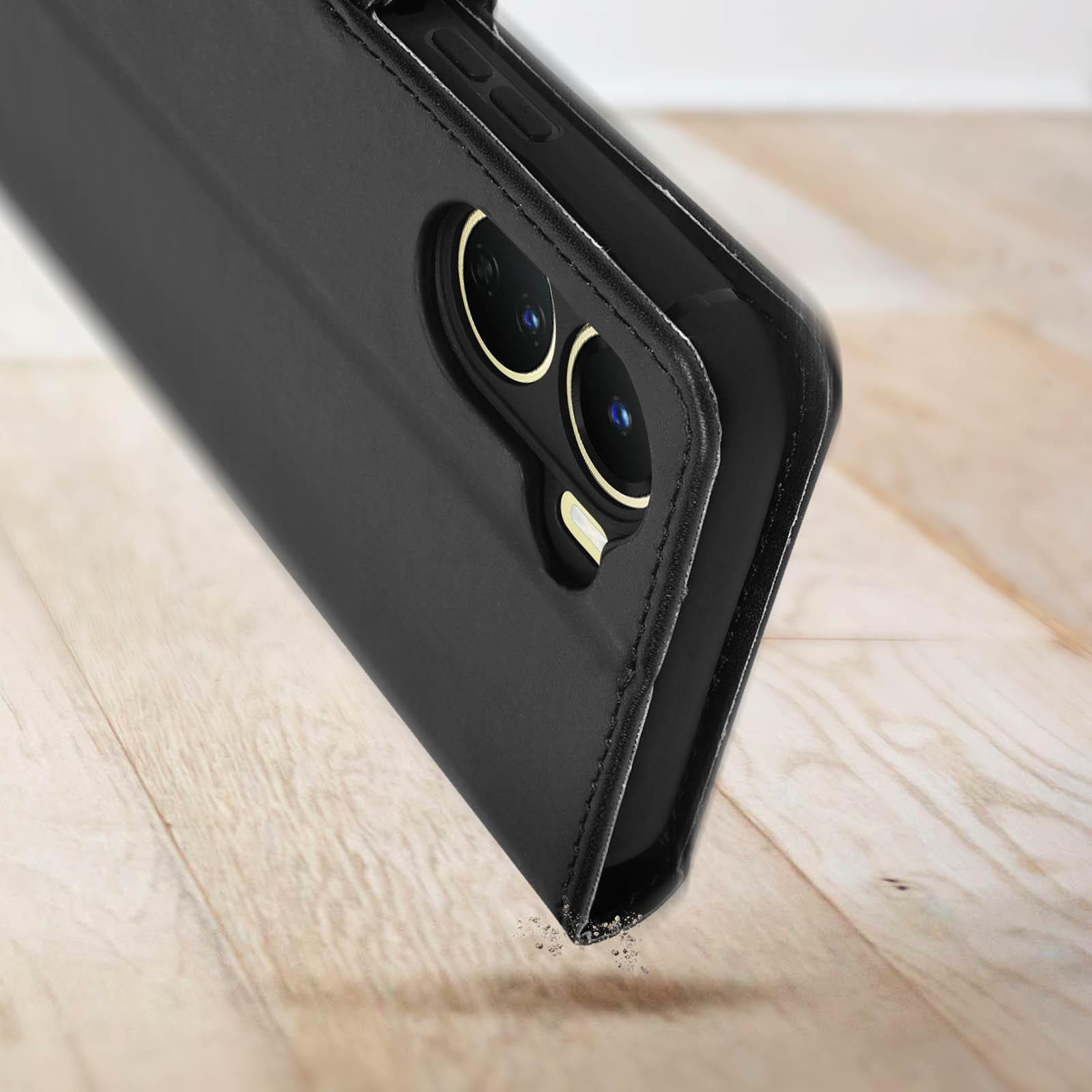 Telefono nero con doppie lenti della fotocamera. Appoggiato su una superficie in legno.