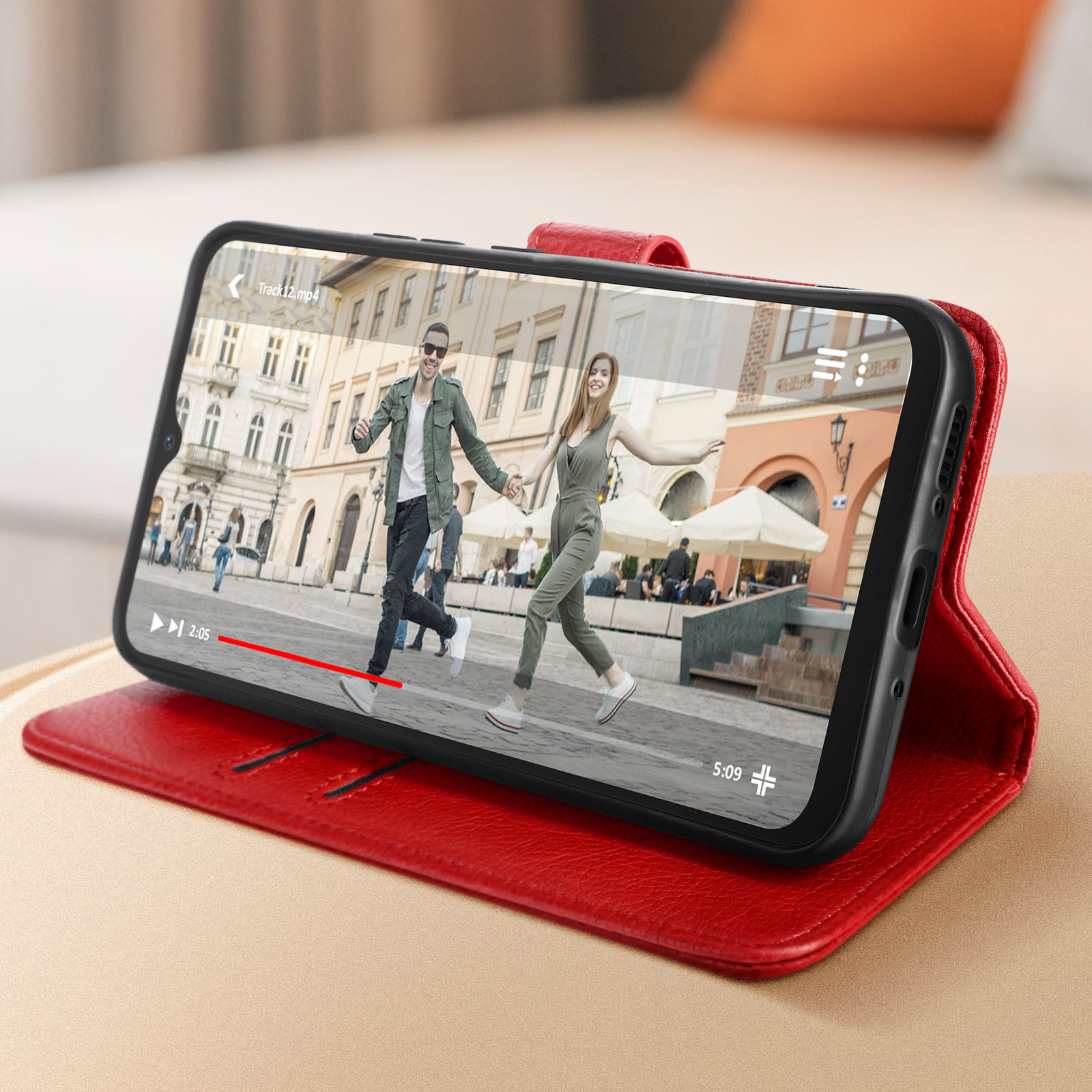Telefono che mostra un video di una coppia che si tiene per mano in una città, in una custodia rossa.