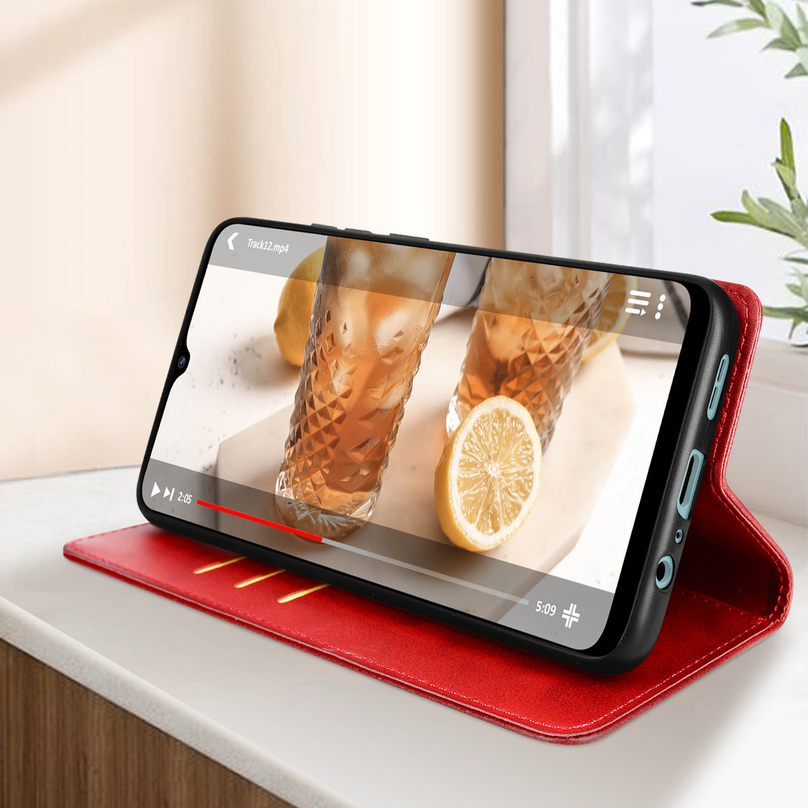Coque de téléphone rouge ouverte sur une table, lisant une vidéo avec un citron sur l'écran.