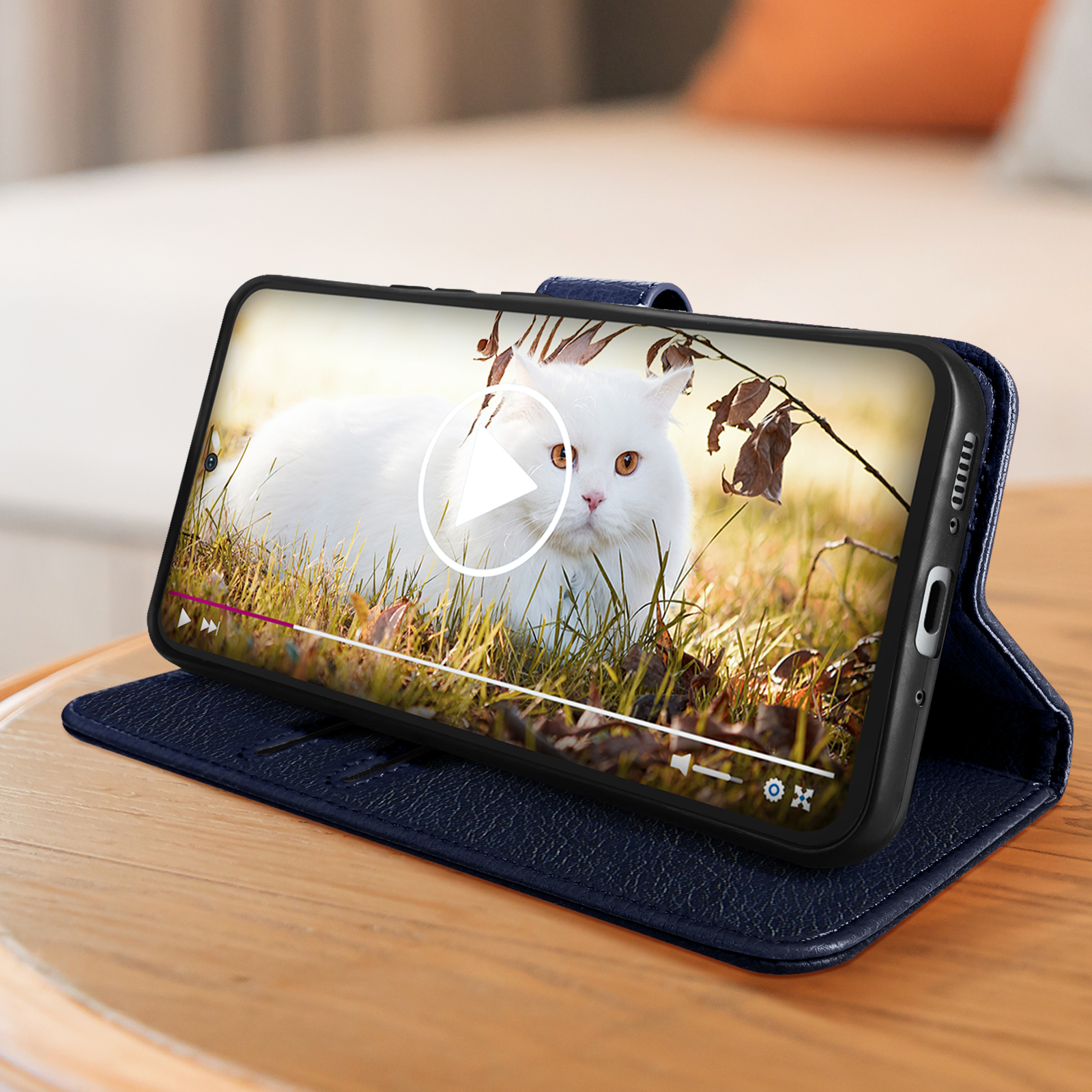 Ein Telefon in einer blauen Hülle zeigt ein Video einer weißen Katze.