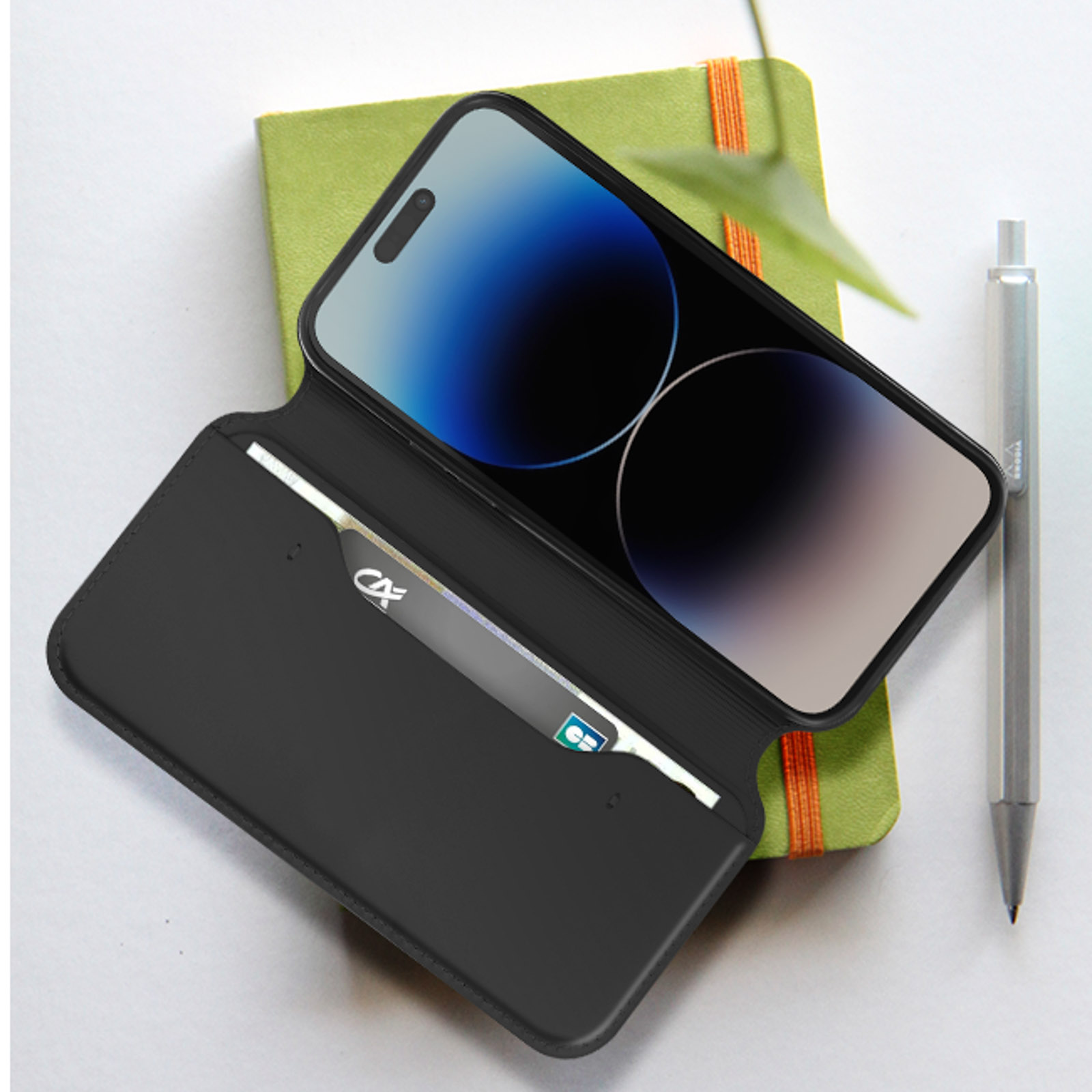 Custodia nera aperta, con telefono e carta di credito. Sfondo taccuino verde.