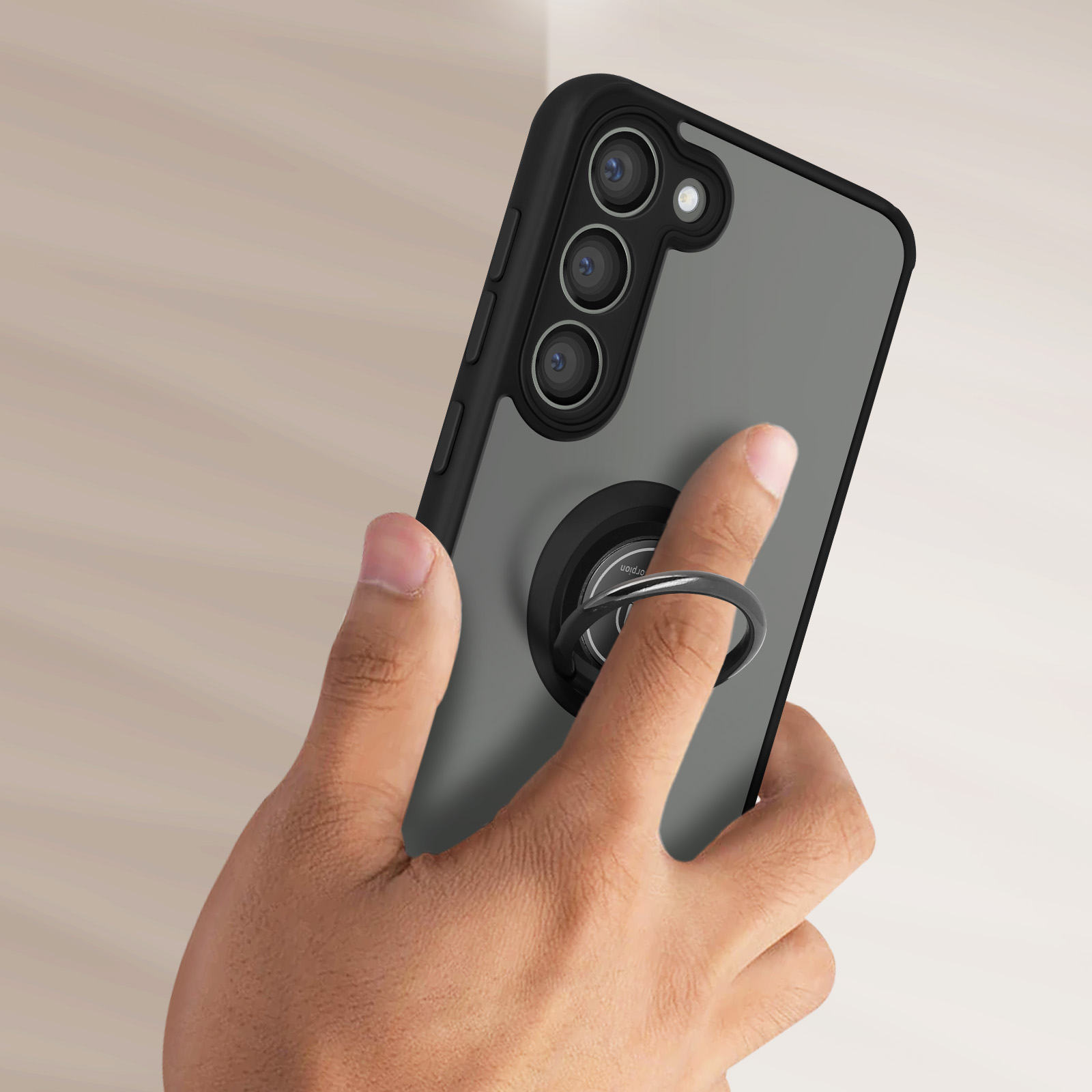 Mano che tiene un telefono con un supporto ad anello collegato. Il telefono è nero e grigio.