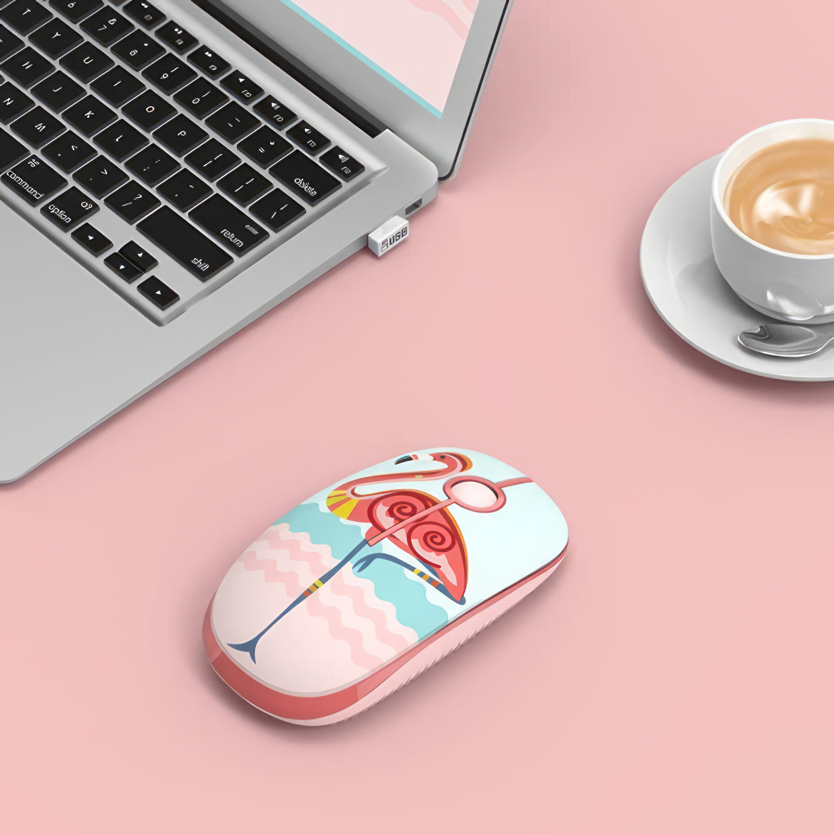 Eine Maus im Flamingo-Design neben Laptop und Kaffee.