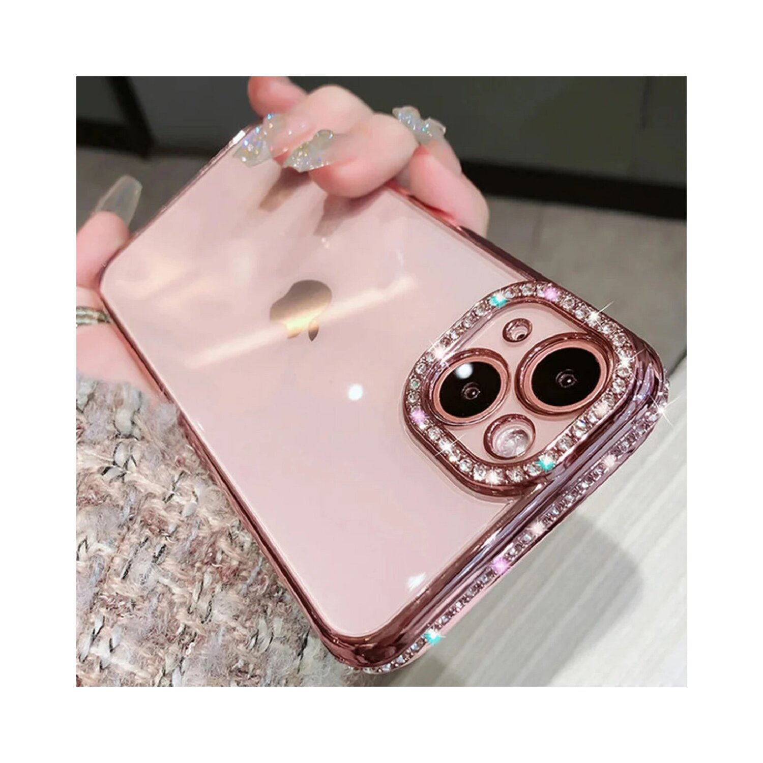 Custodia per telefono rosa con diamanti attorno agli obiettivi della fotocamera, mano che la tiene.