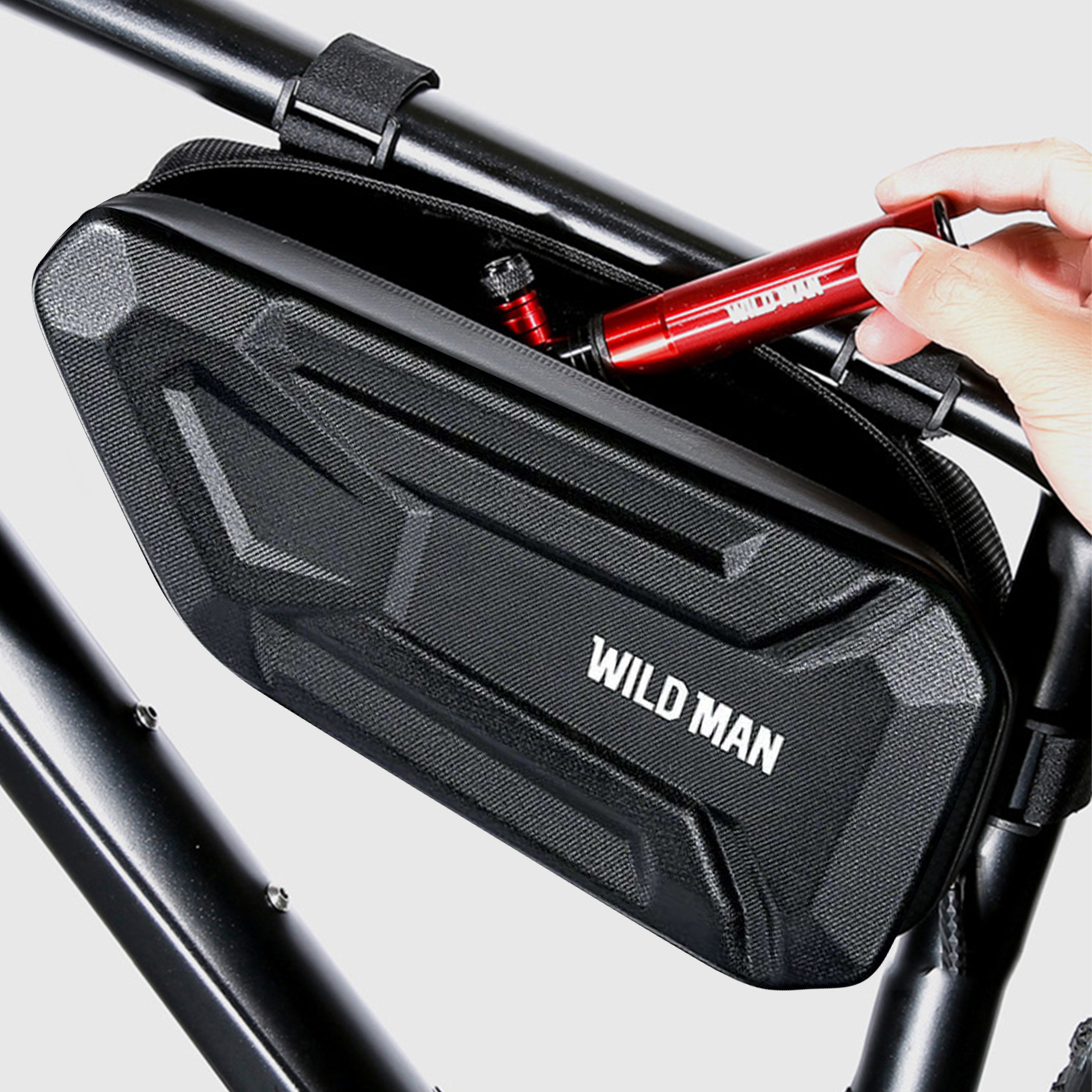 Eine Person hält ein rotes Zubehörteil in einer schwarzen Fahrradtasche mit "WILD MAN".