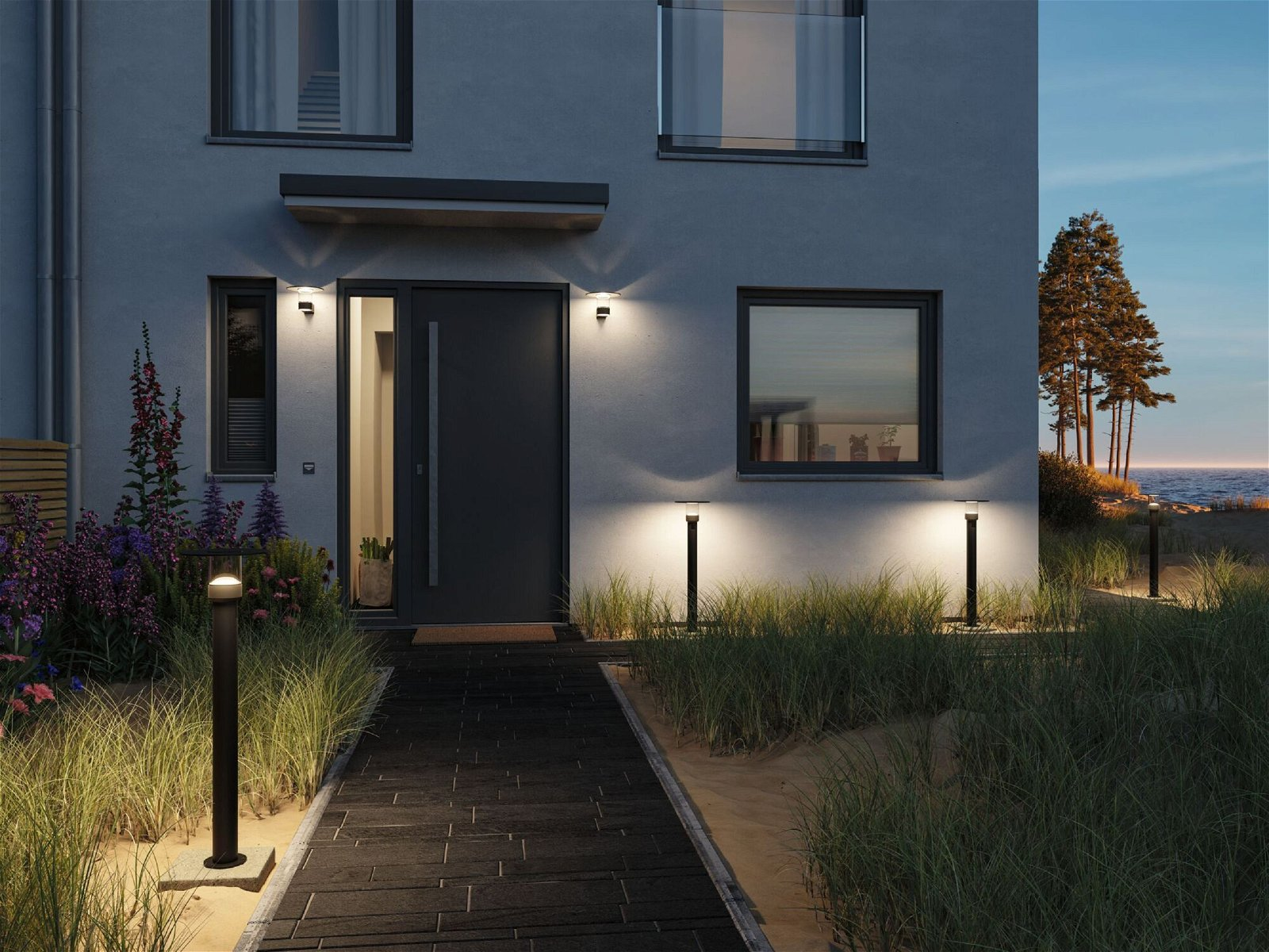 Fasada domu z ciemnymi drzwiami i światłami w nocy, ze ścieżką.