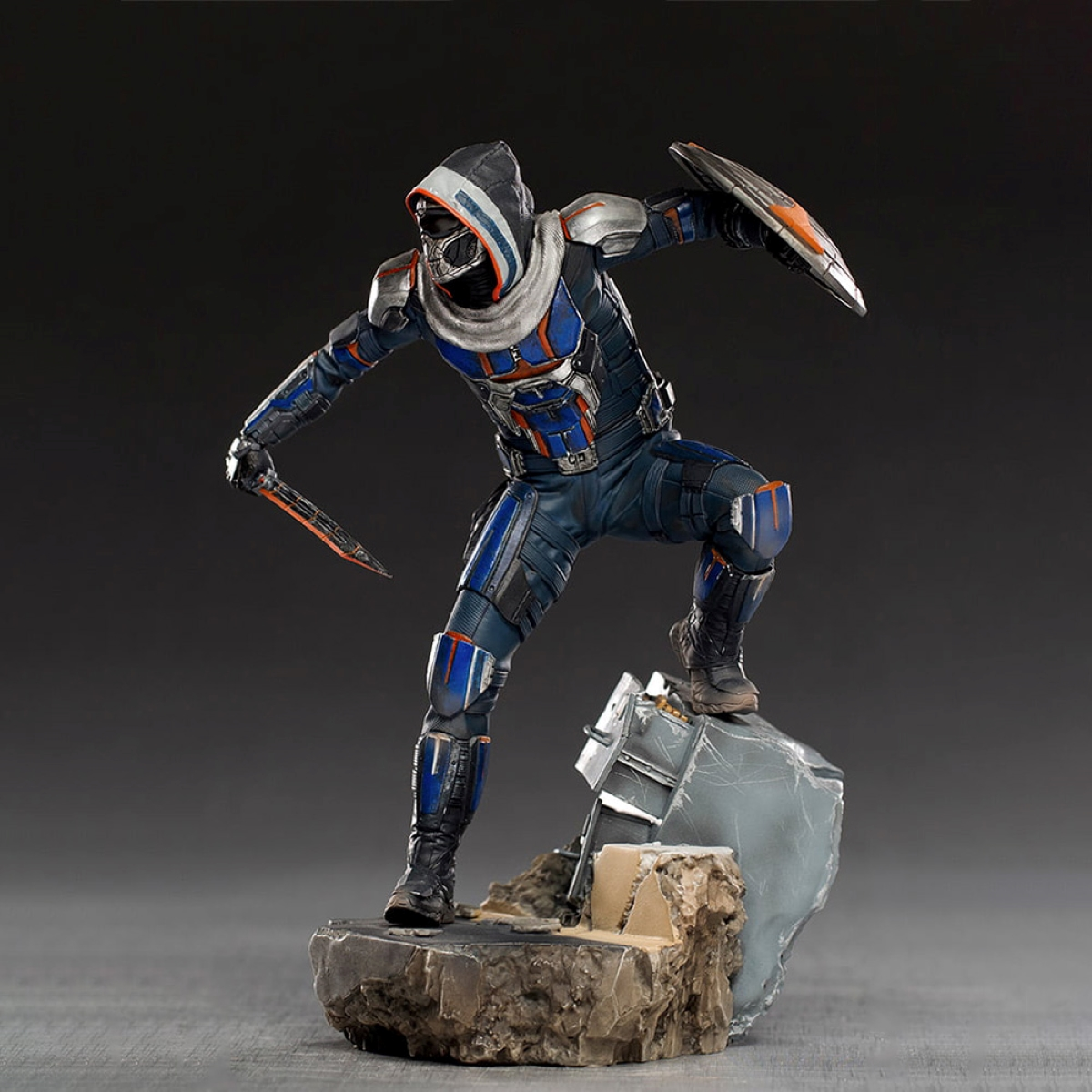 Eine Statue einer Figur in einem schwarz-blauen Anzug mit Schild und Messer.