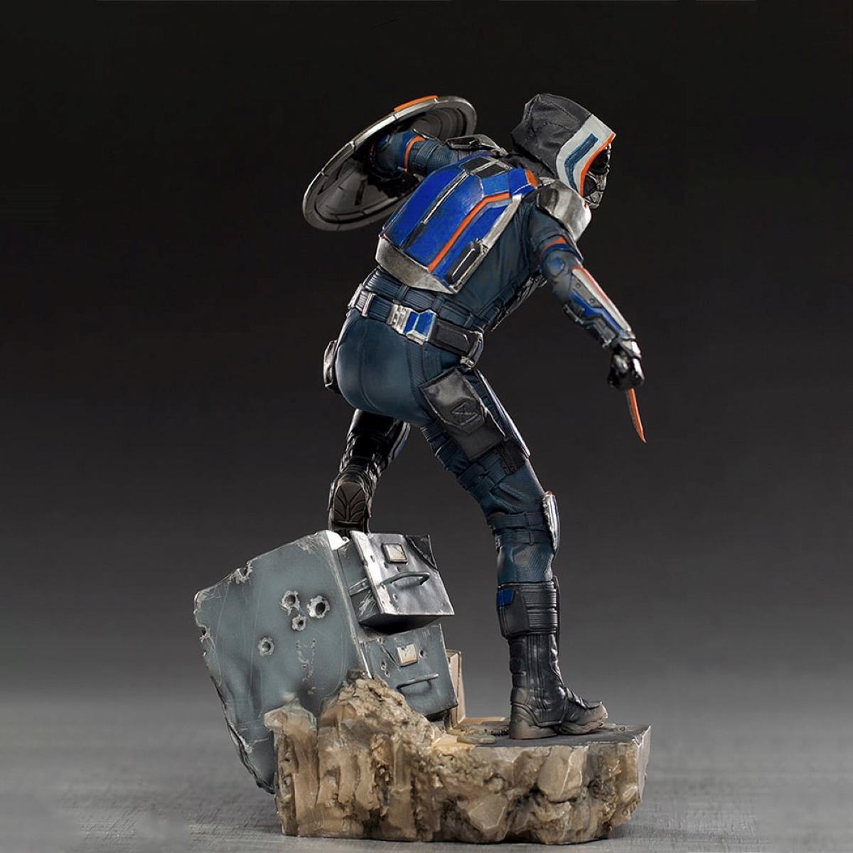 Taskmaster-Figur, in Kampfpose, mit Schild und Messer. Dunkler Hintergrund.
