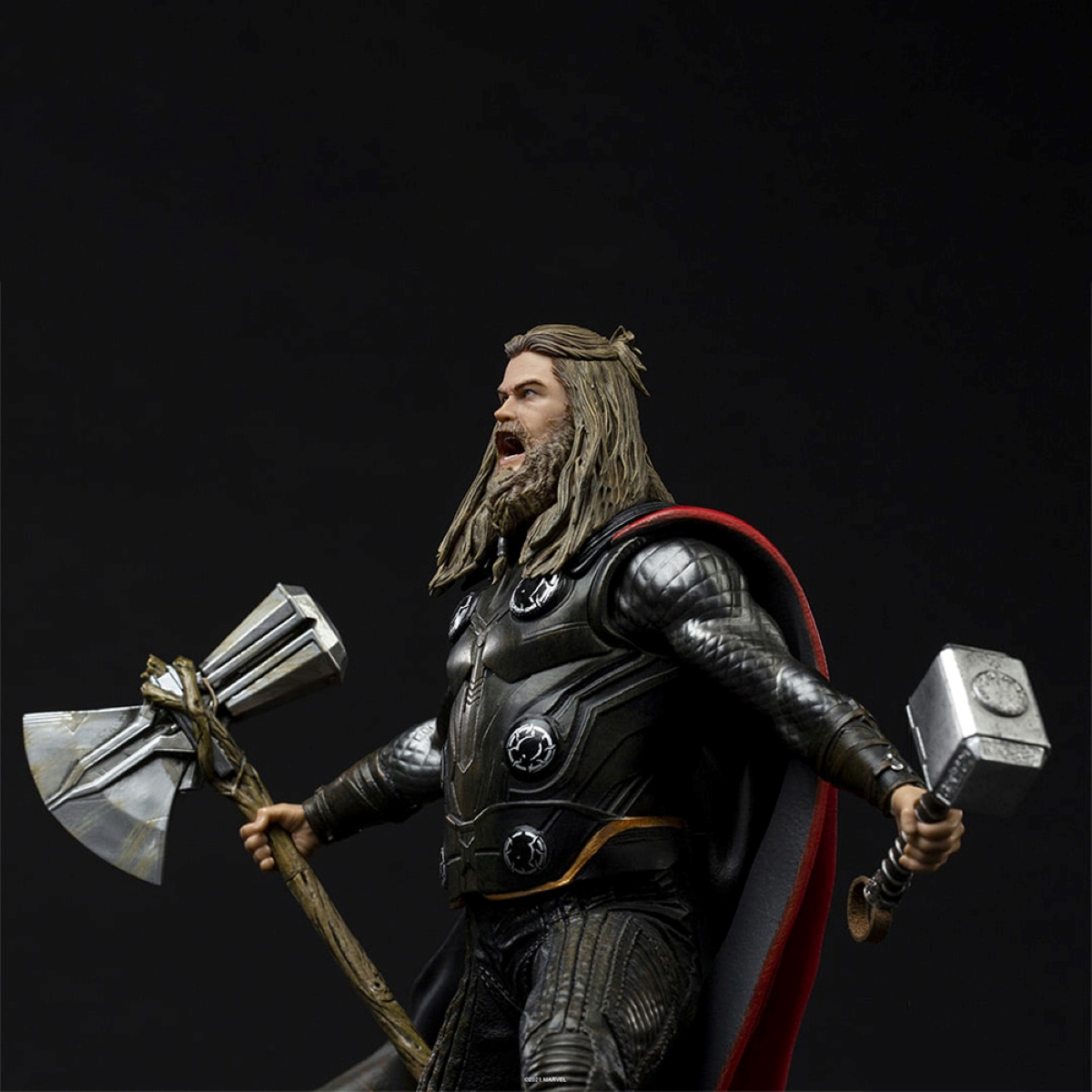 Eine Statue von Thor, der zwei Waffen hält, eine Axt und einen Hammer, vor schwarzem Hintergrund.