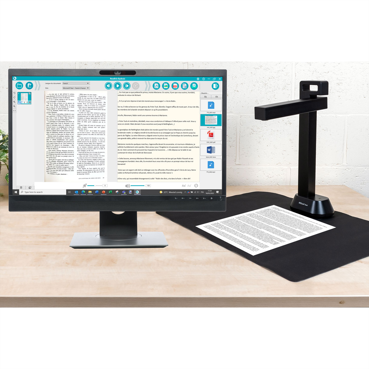Dispositivo scanner accanto a uno schermo del computer e a un documento su un tappetino nero.