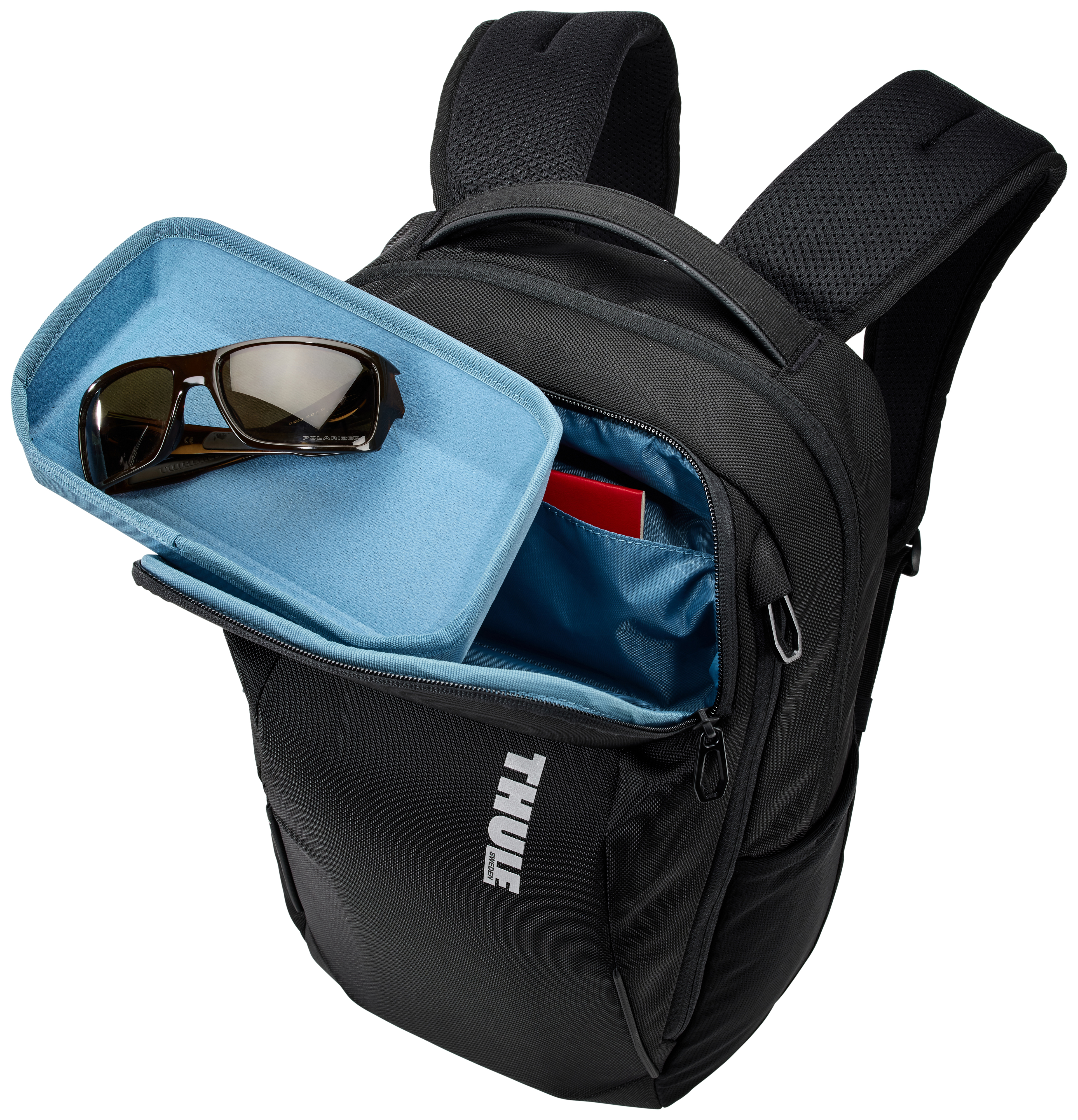 Schwarzer Rucksack mit offener Tasche. Sonnenbrille und ein roter Gegenstand sind im blauen Fach sichtbar.
