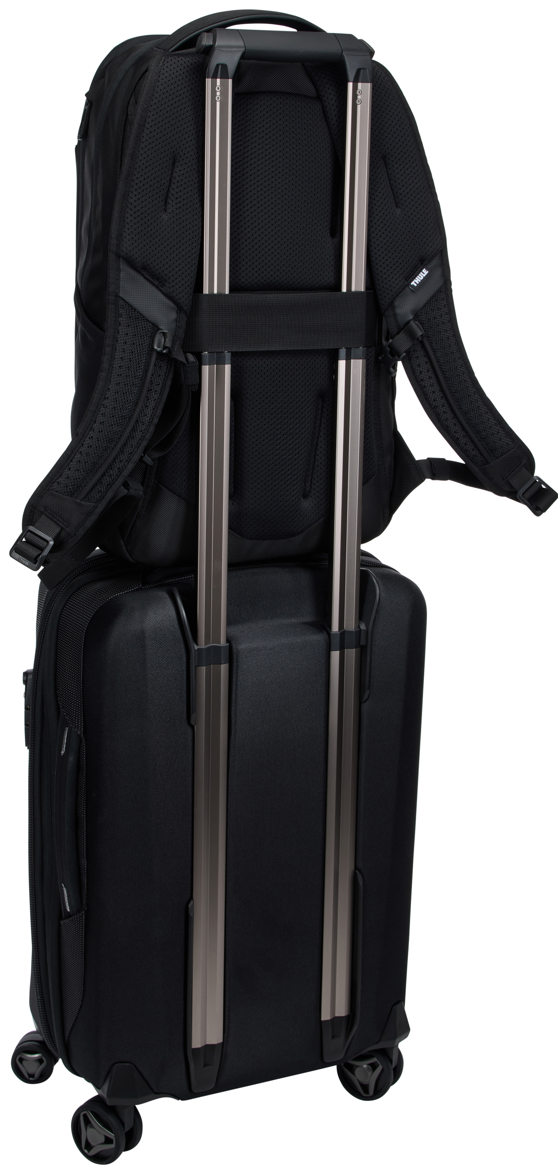Schwarzer Rucksack auf einem schwarzen Koffer mit silbernen Griffen. Der Hintergrund ist weiß.