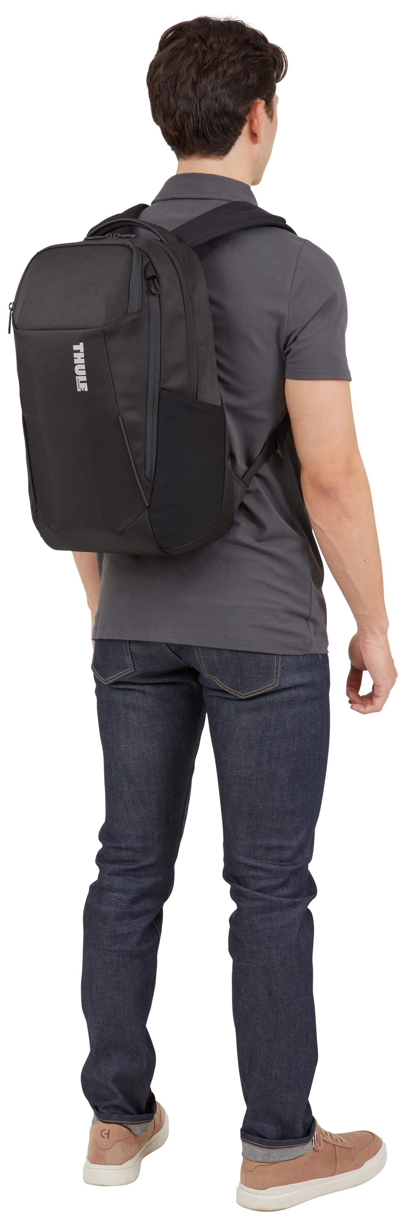 Eine Person mit einem schwarzen Rucksack, die dem Betrachter den Rücken zukehrt. Die Tasche hat ein weißes Logo.