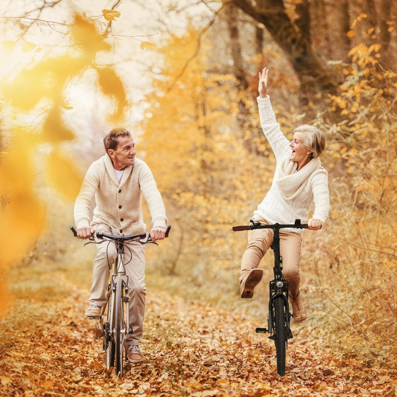 Zwei Personen fahren im Herbst Fahrrad, eine winkt.