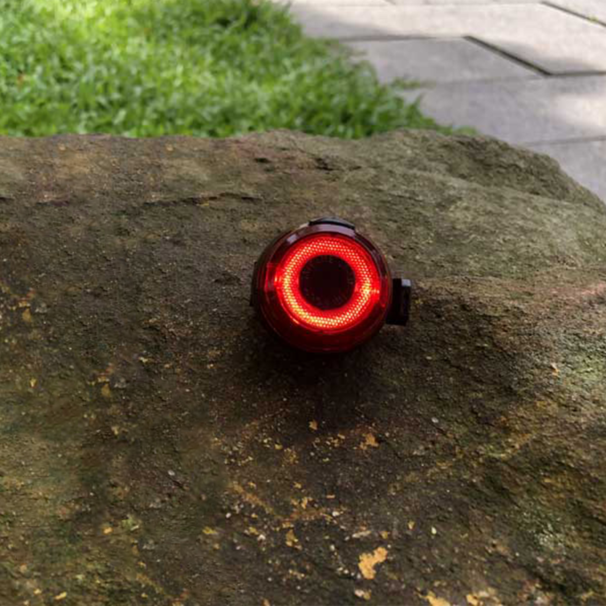 Ein rotes Fahrradlicht auf einem Stein. Es hat eine kreisförmige Form mit rotem Licht.