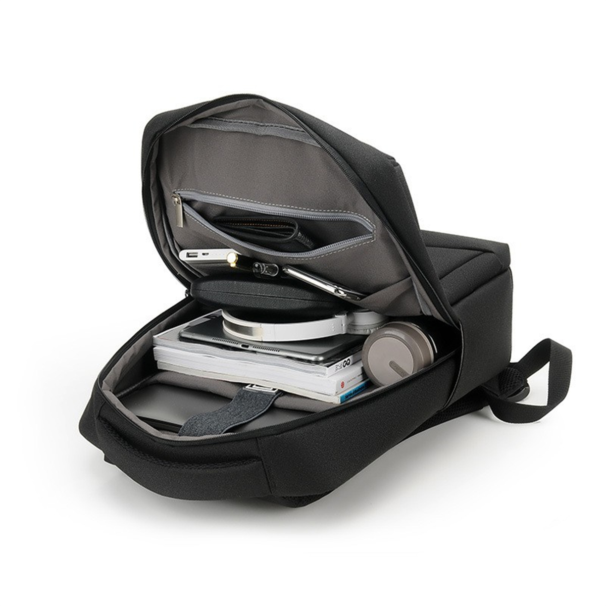 Schwarzer Rucksack offen, Inhalt: Bücher, Laptop, Tablet, Kopfhörer, Stifte und andere Gegenstände.