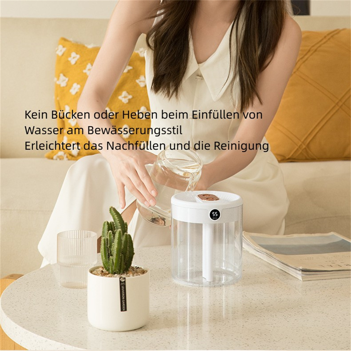 Frau gießt Wasser in einen Luftbefeuchter, Kaktus und Buch auf Tisch.