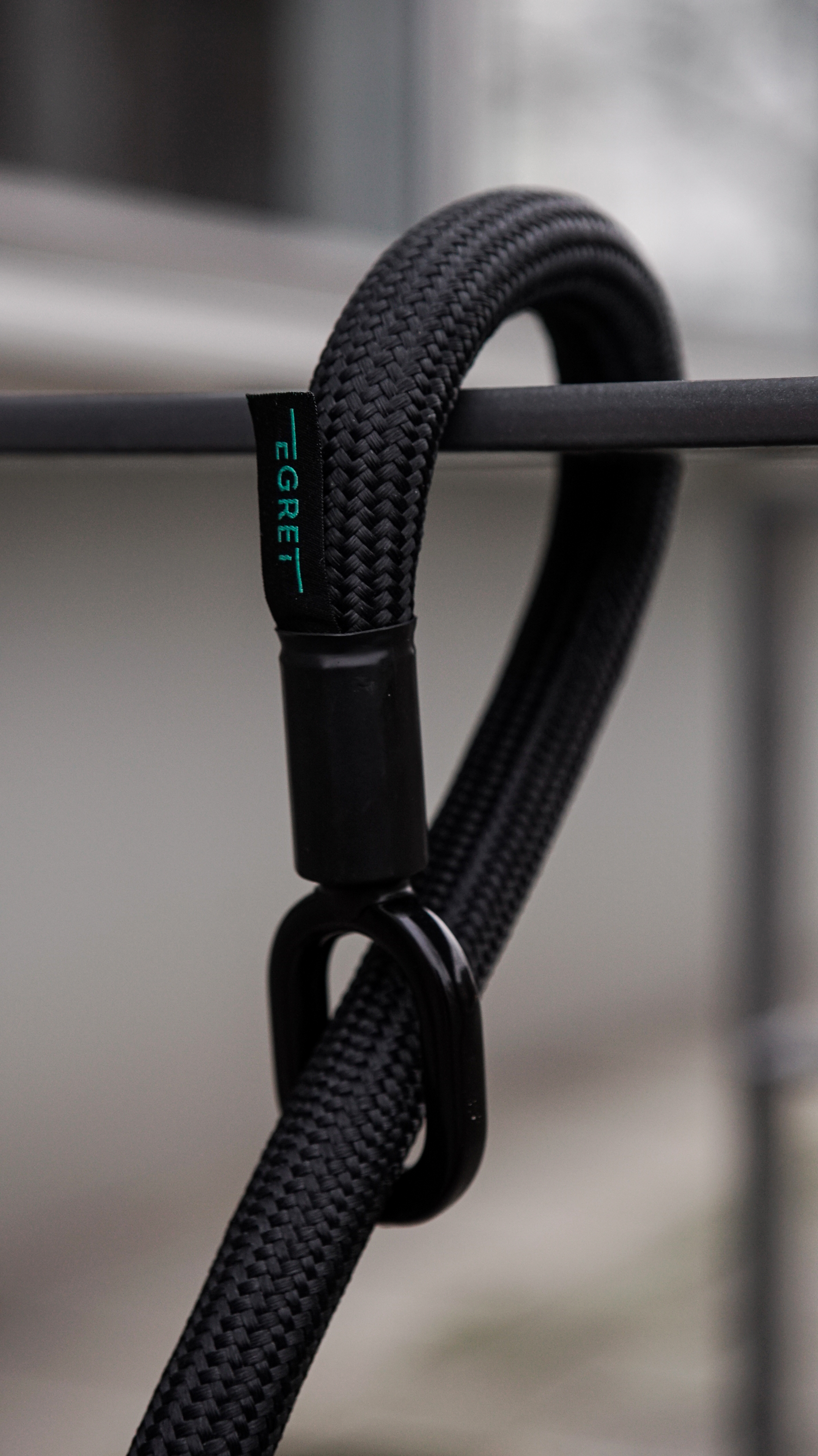 Nahaufnahme eines schwarzen Seils mit einem schwarzen Karabiner und einem Etikett.