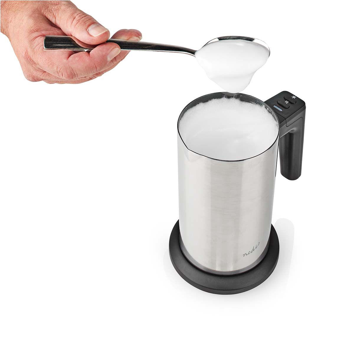 Mano tiene un cucchiaio di schiuma di latte sopra un montalatte.