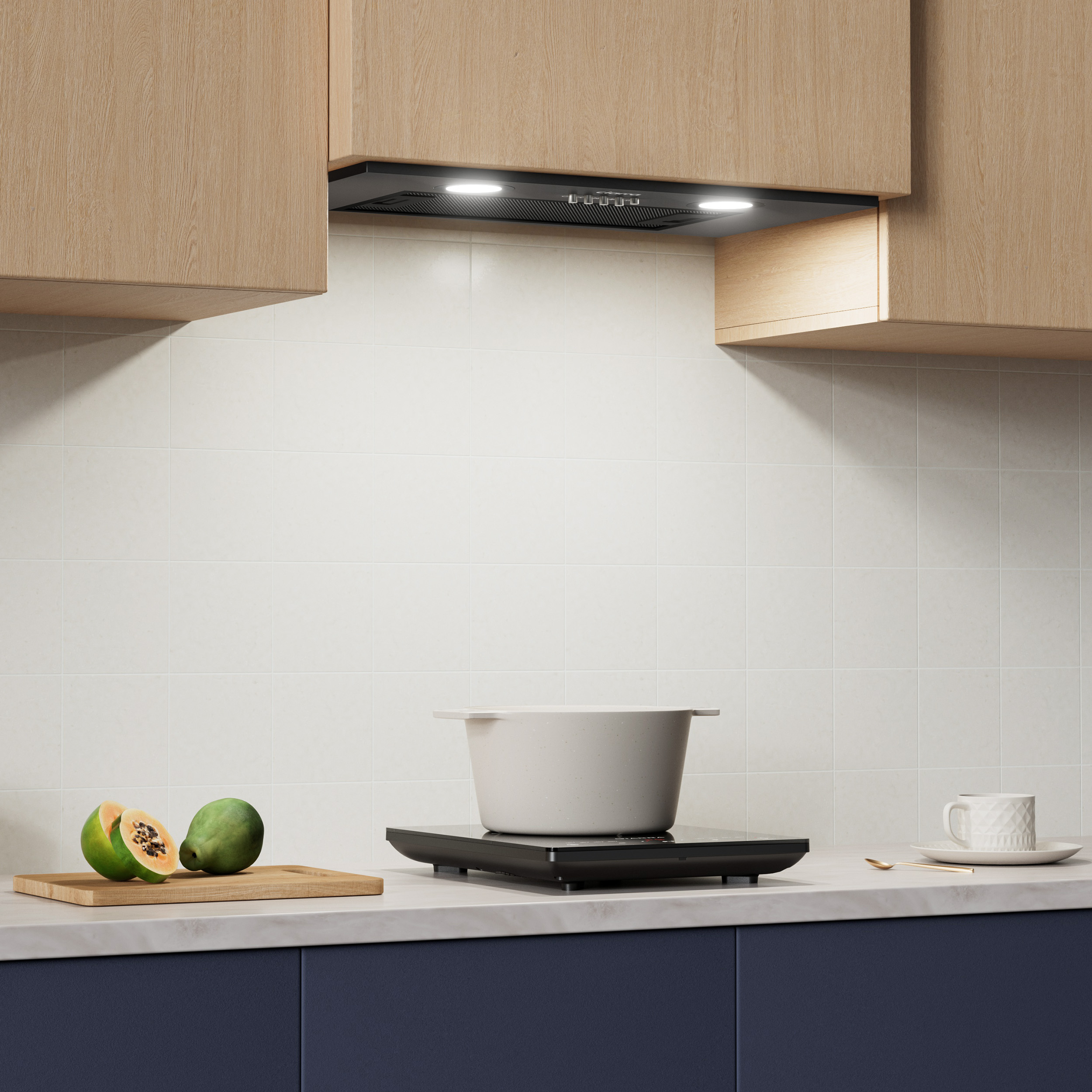 Keuken met afzuigkap, witte en blauwe kasten. Een pan staat op een kookplaat.