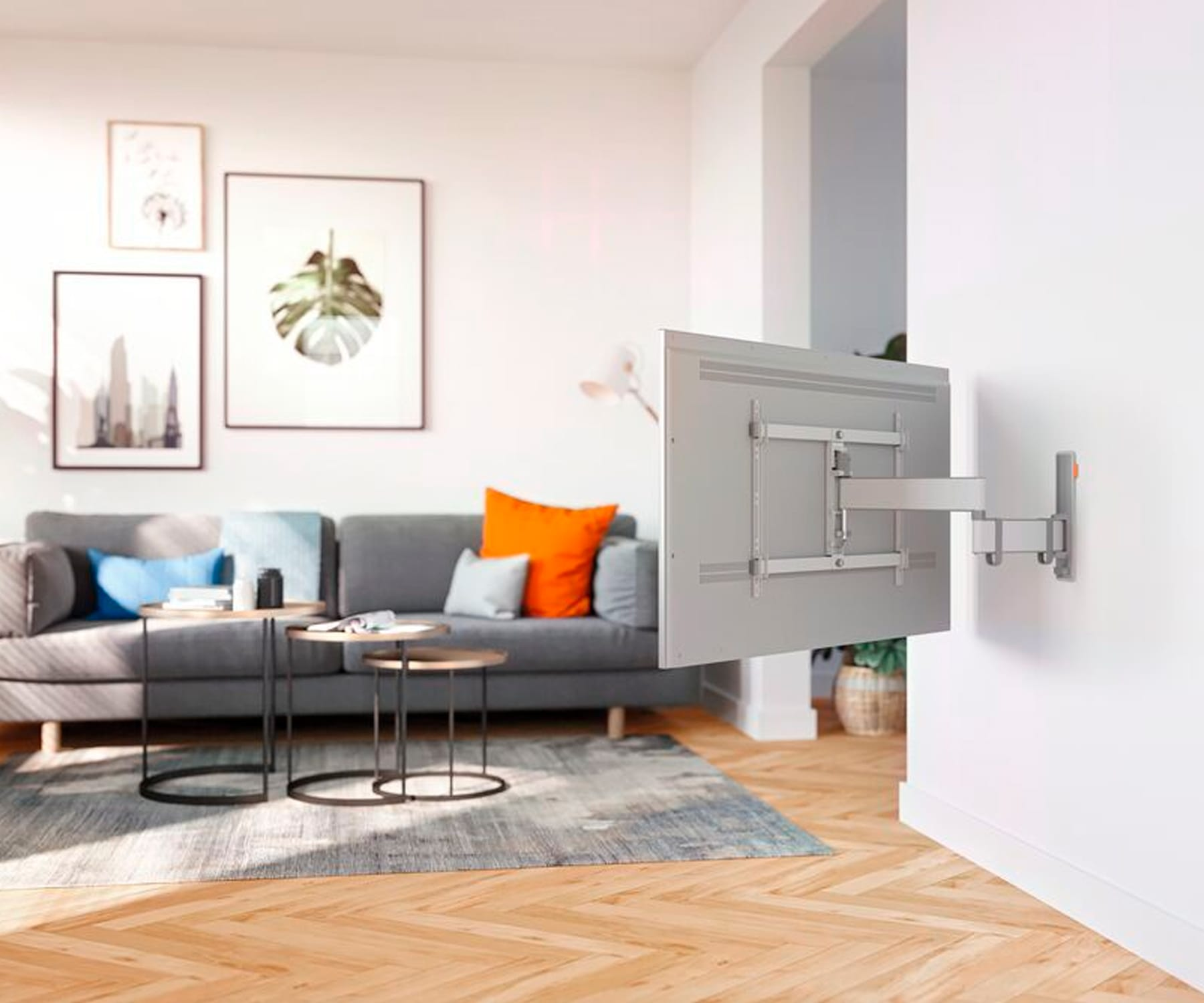 Salon z telewizorem na ścianie, sofą, stolikami kawowymi i dziełami sztuki. Drewniana podłoga.