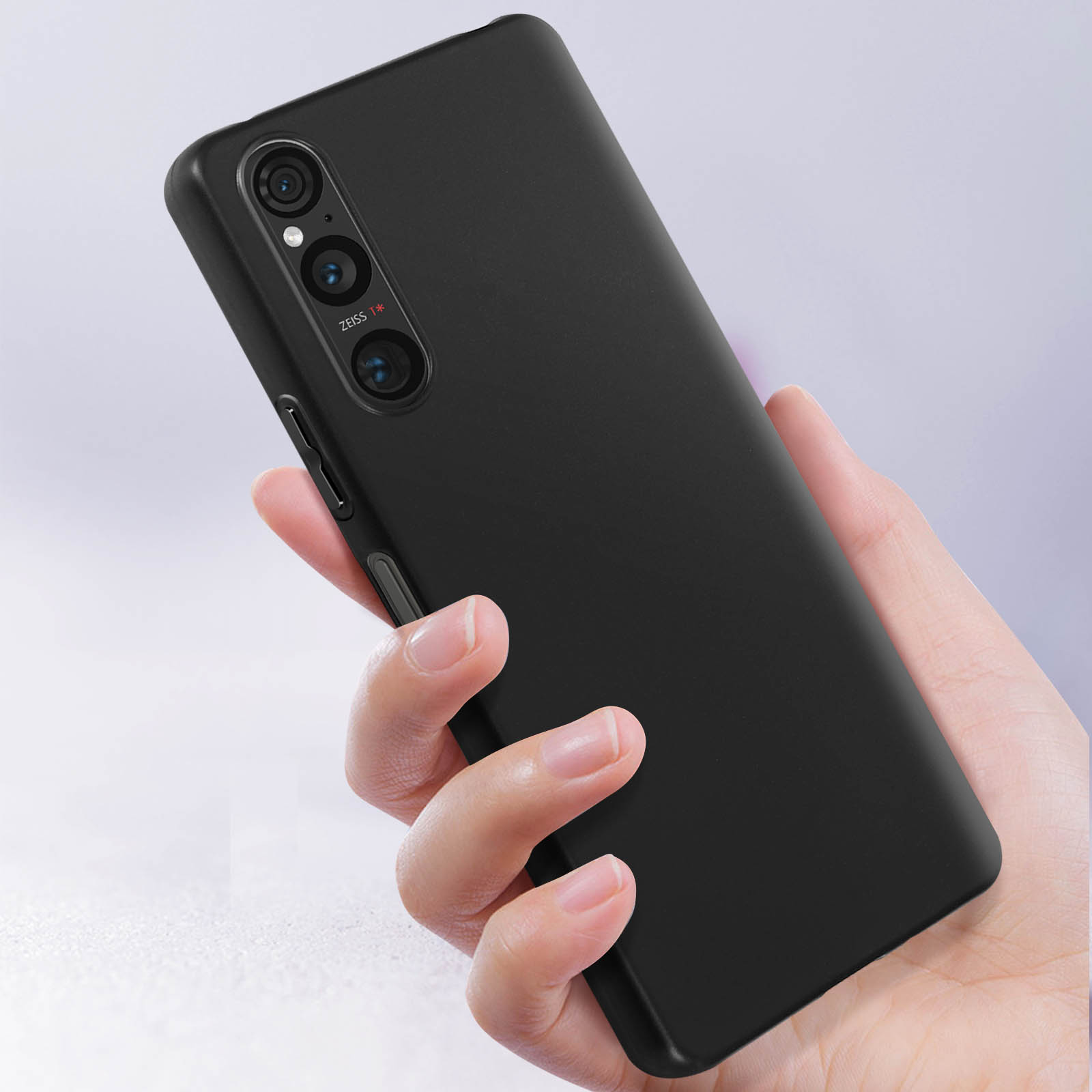 Mano che tiene un telefono nero con tre fotocamere. Custodia nera. Marchio dell'obiettivo Zeiss.