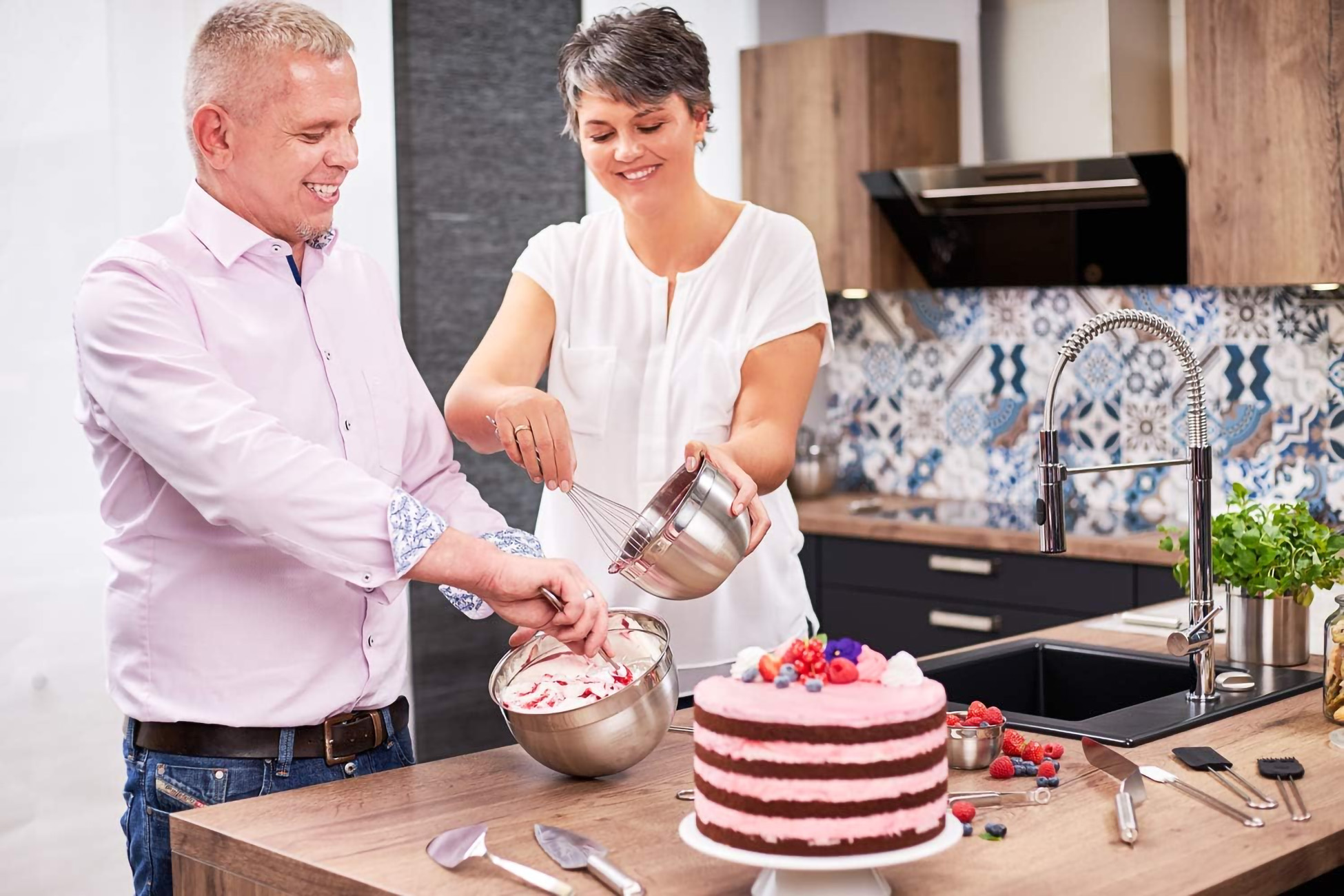 Ein Paar dekoriert gemeinsam einen Kuchen in einer modernen Küchenumgebung.