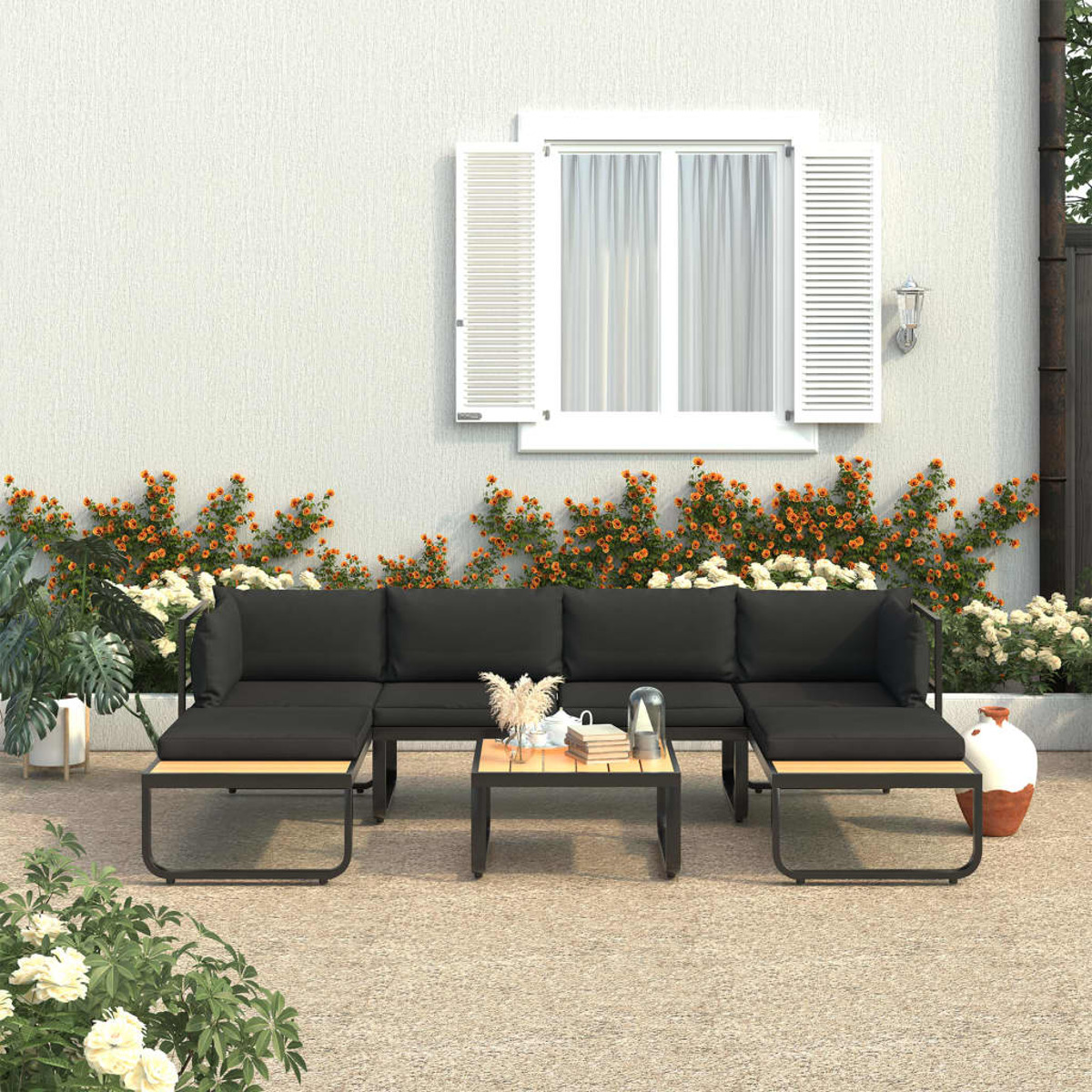Ein Terrassenset mit schwarzen Kissen und einem Tisch vor einer Wand.