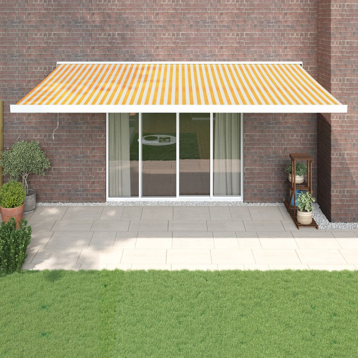 Gelb-weiß gestreifte Markise über einer Terrassentür mit Backsteinaußenwand.