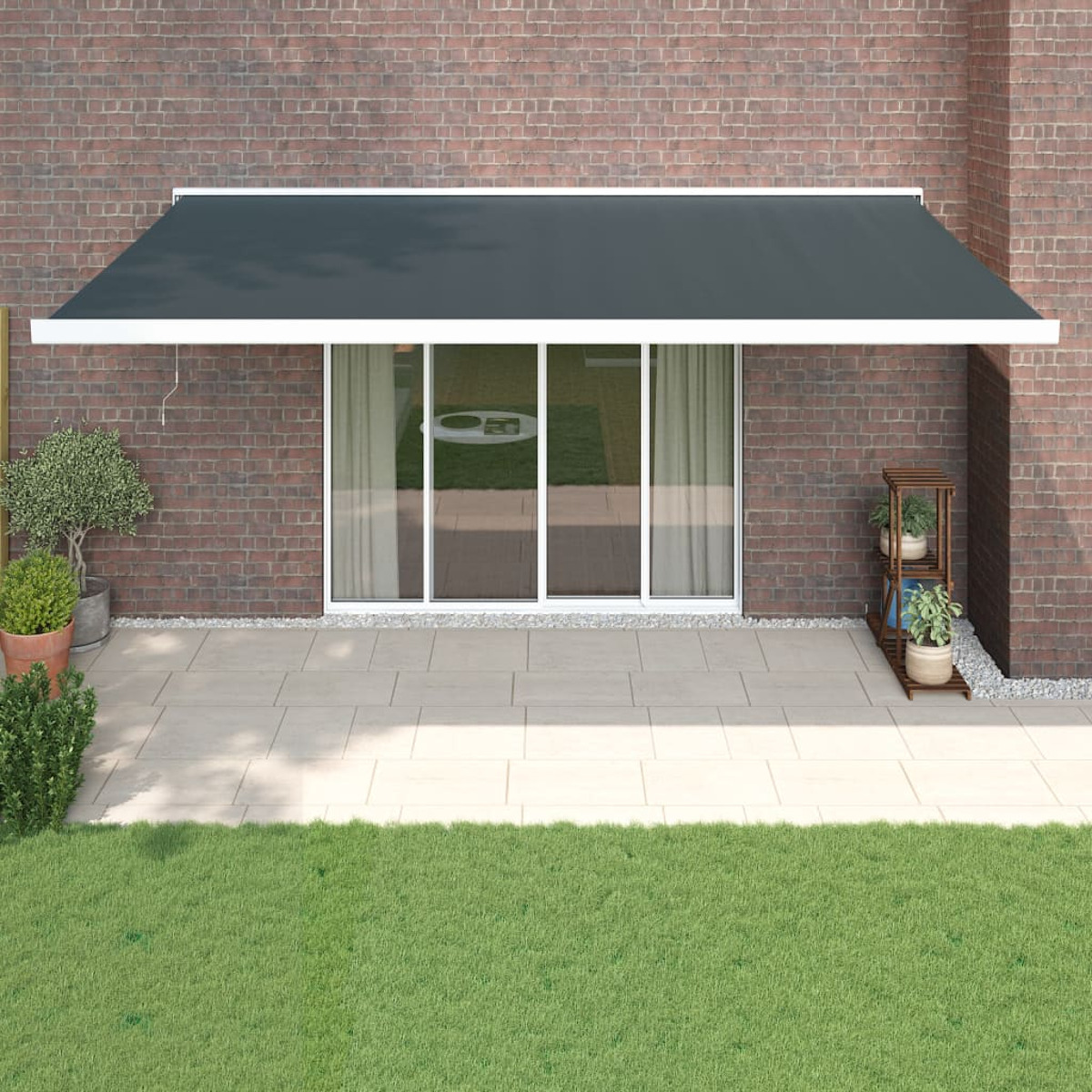Dunkelgraue Markise über Terrassentür mit Backsteinaußenwand und grünem Rasen.