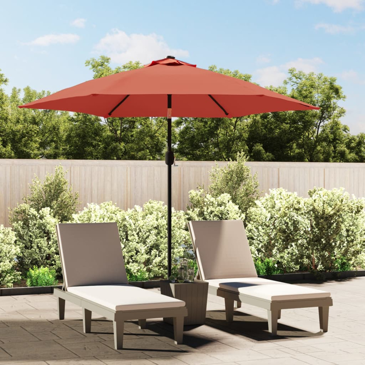 Eine Terrasse mit rotem Sonnenschirm, zwei Liegestühlen und einem kleinen Tisch.