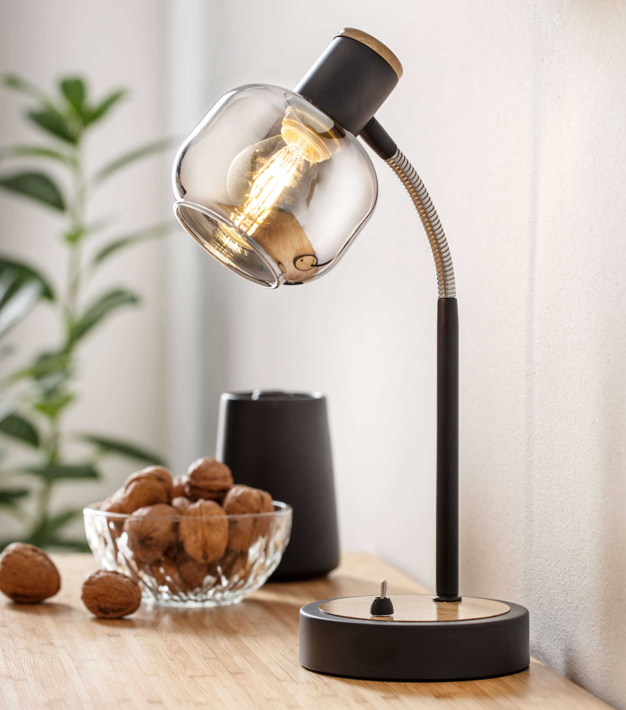 Schwarze Schreibtischlampe mit Glasschirm, Walnüsse und ein schwarzes Objekt.