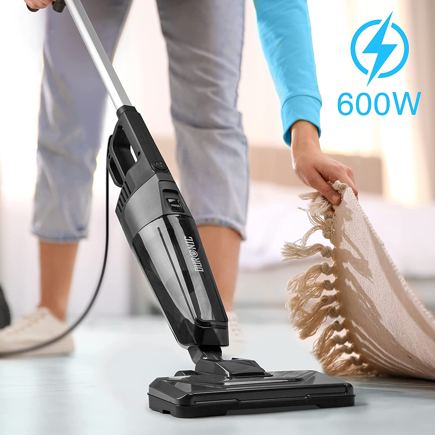 Person saugt einen Teppich mit einem schwarz-grauen Staubsauger. Energiesymbol.